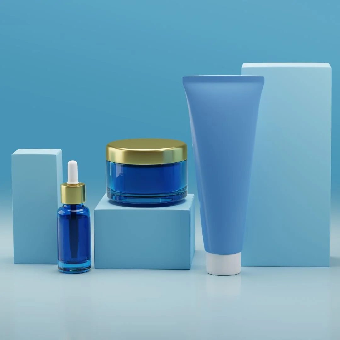 Beauty skincare products in blue and gold packaging on blue geometric stands against a light blue background.