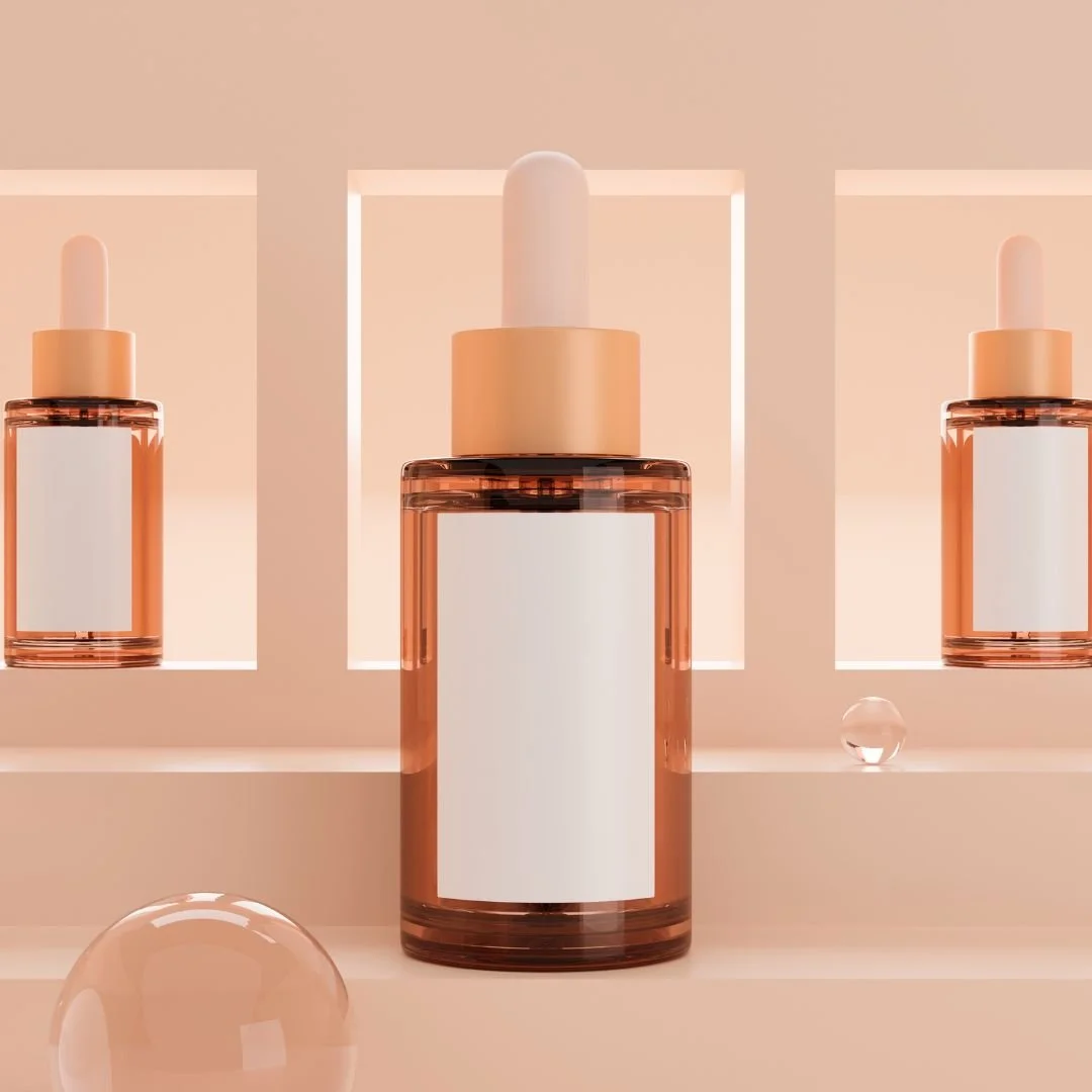 Three identical cosmetic glass bottles with dropper caps, featured in a minimalist and soft peach-colored setting with geometric backgrounds and glass spheres.