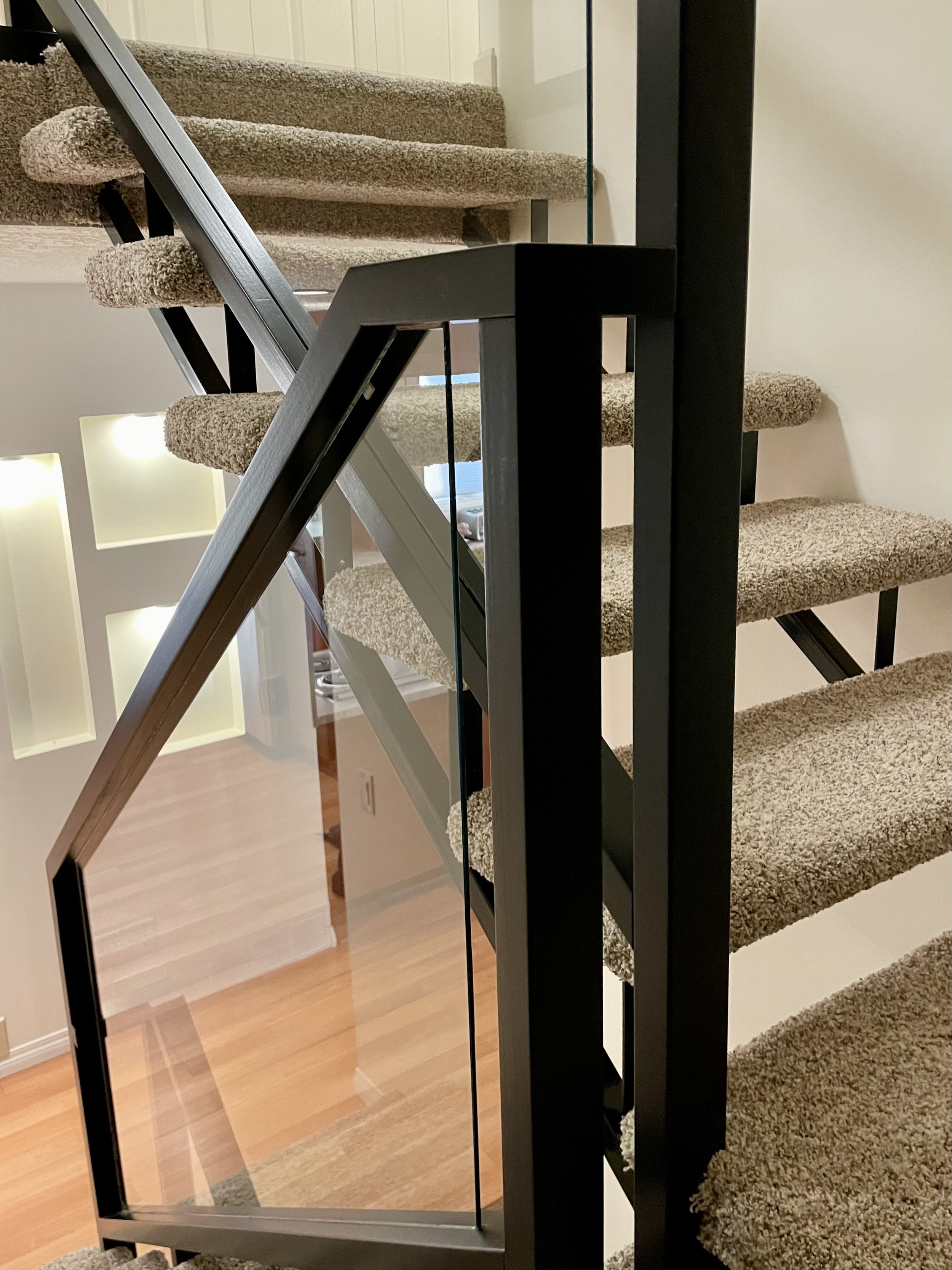 Modern staircase with carpeted steps and glass railing