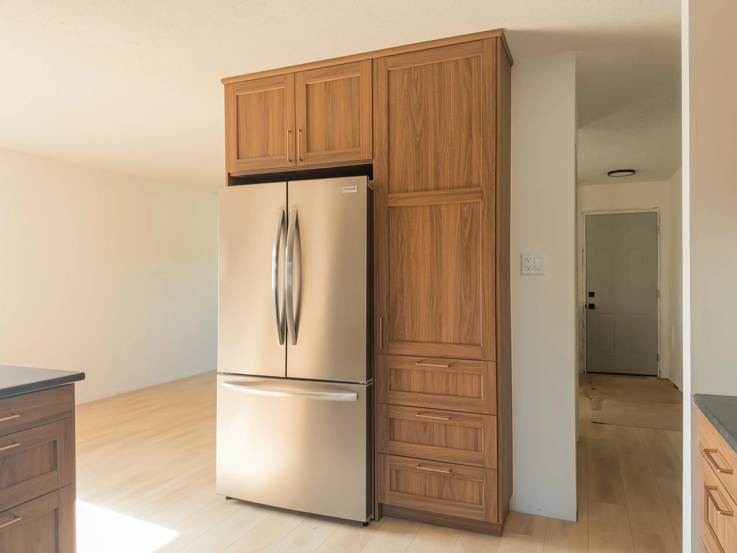 Kitchen with stainless steel refrigerator, wooden cabinets, and beige walls.