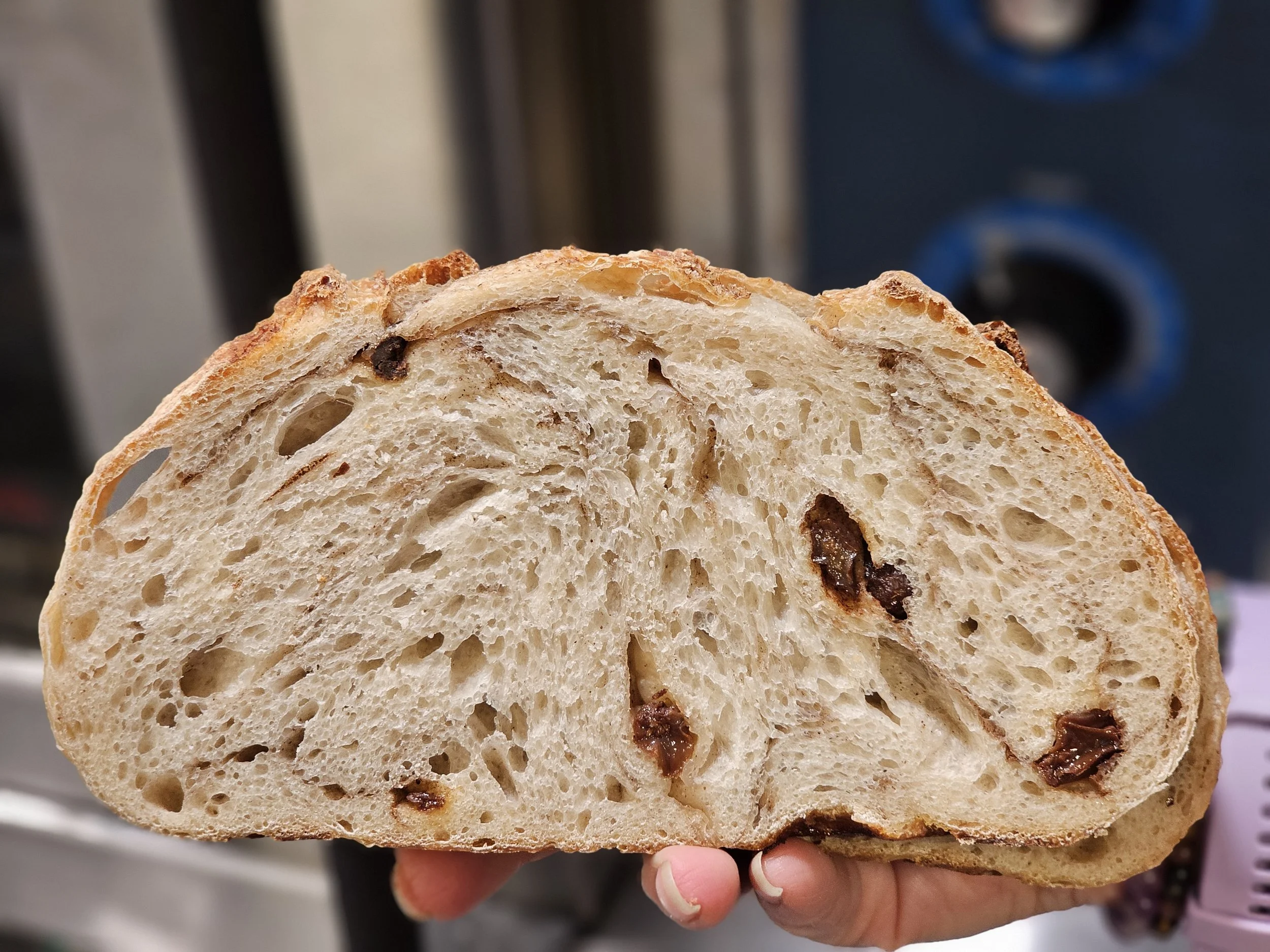 A hand holding a slice of bread with chocolate chips inside.