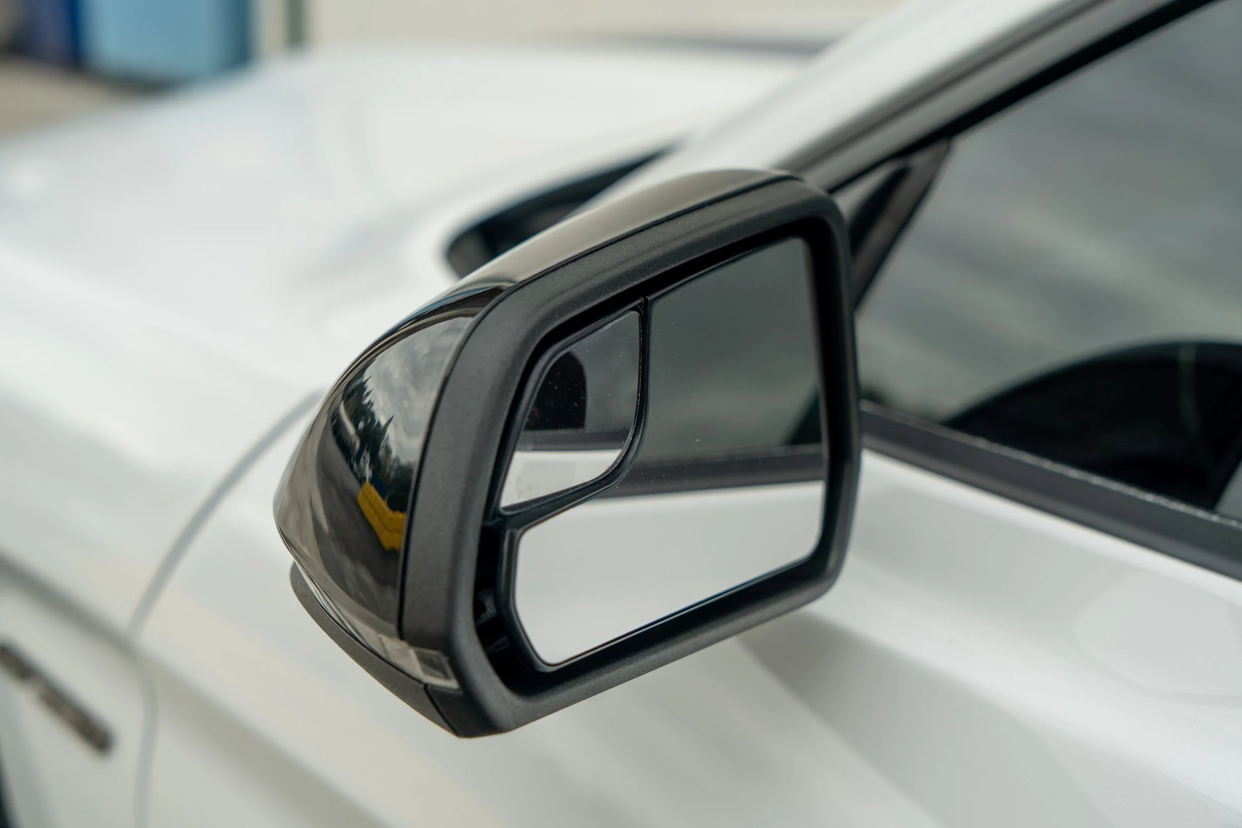 Close-up of a vehicle's side mirror with a built-in turn signal indicator on a white car.