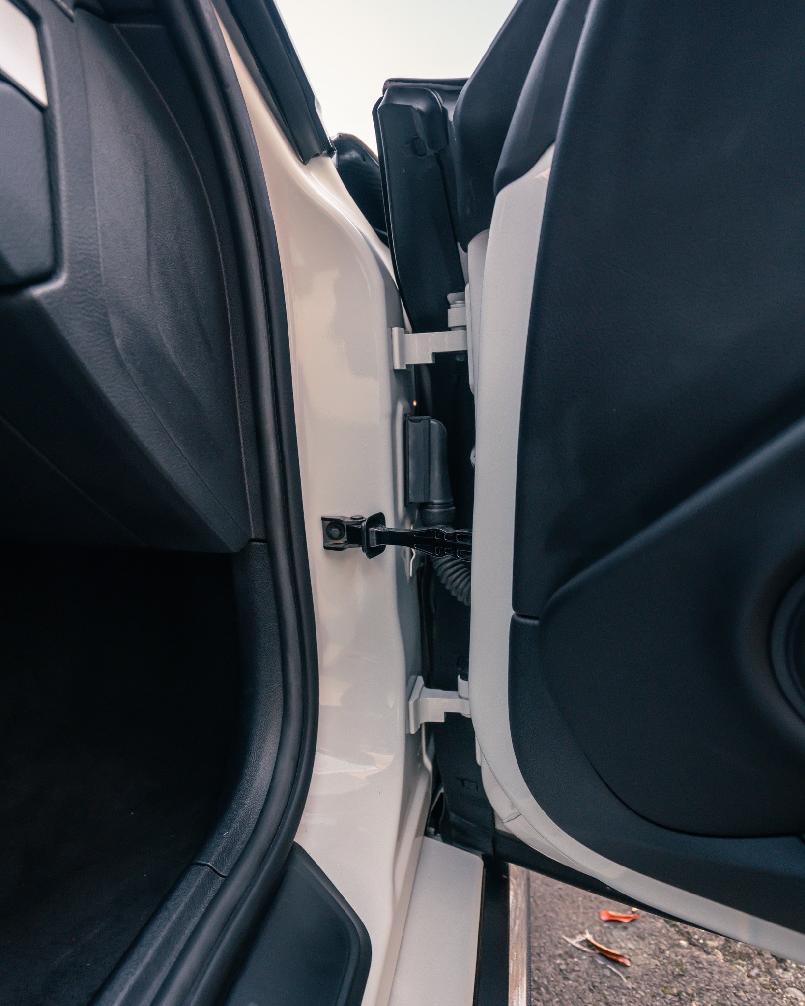 Open car door showing door hinge and interior threshold of a vehicle.