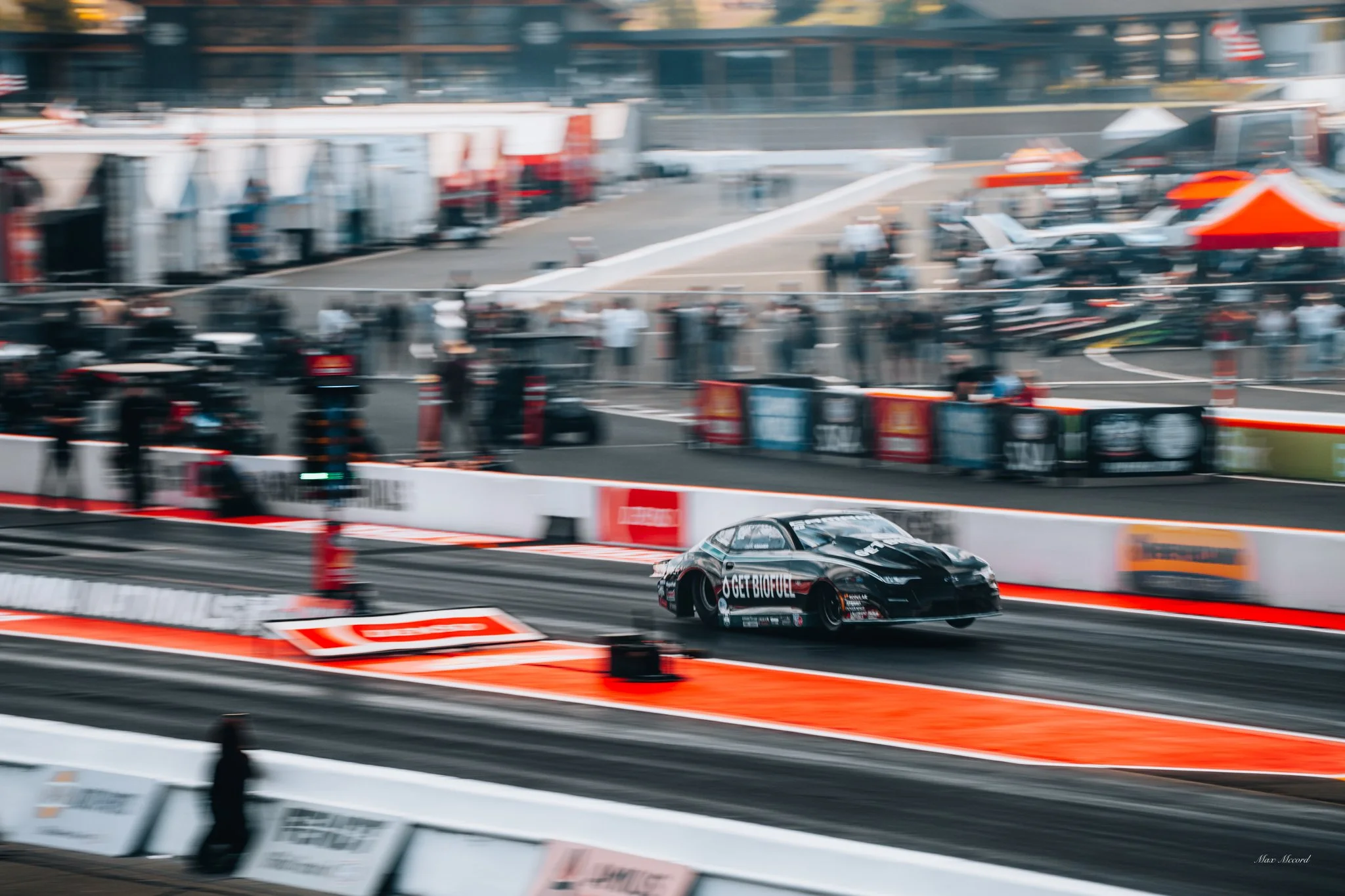 A black racing car on a race track, with tire smoke and motion blur, during a race event.