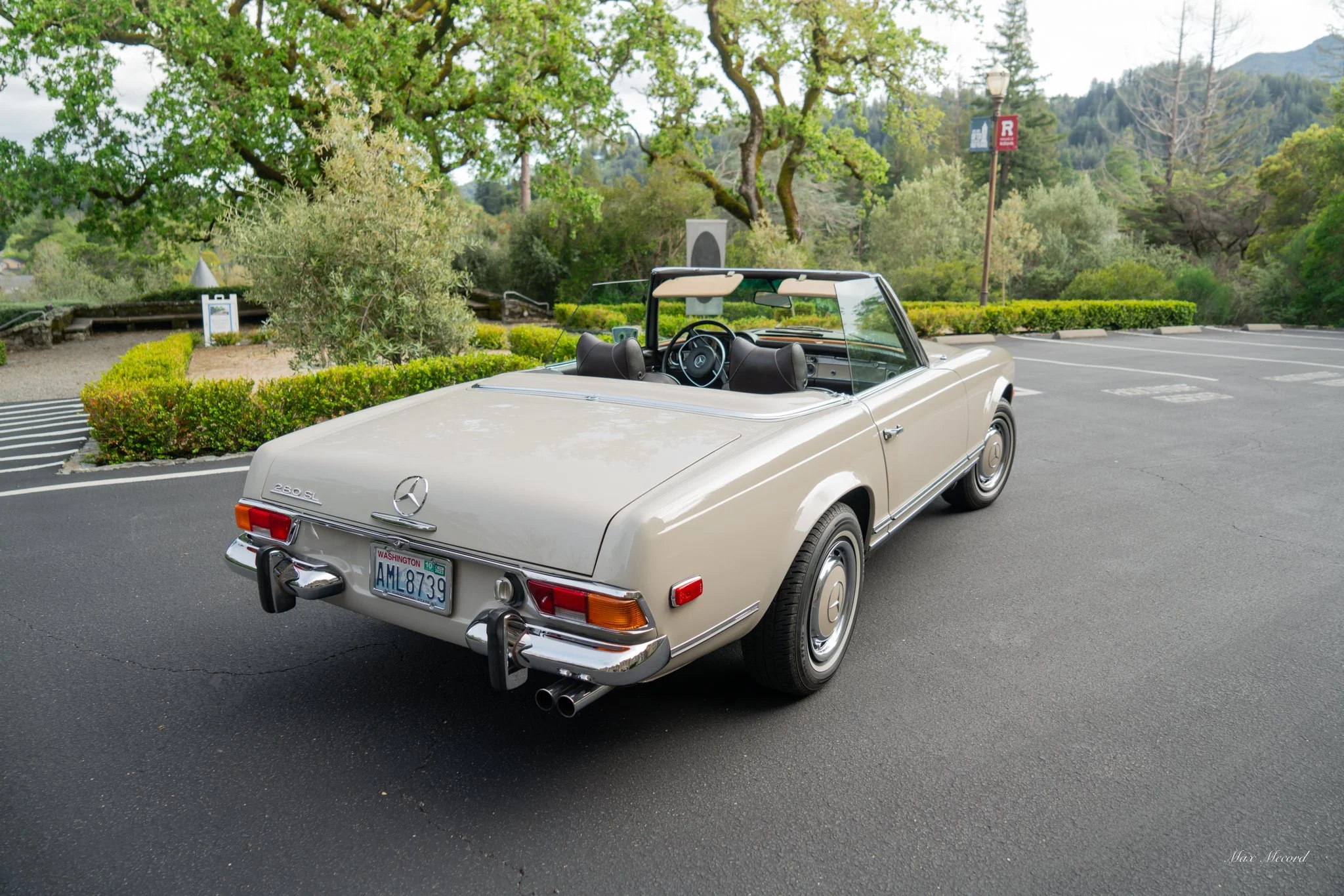 A vintage Mercedes-Benz 280 SL convertible car parked in an outdoor parking lot.