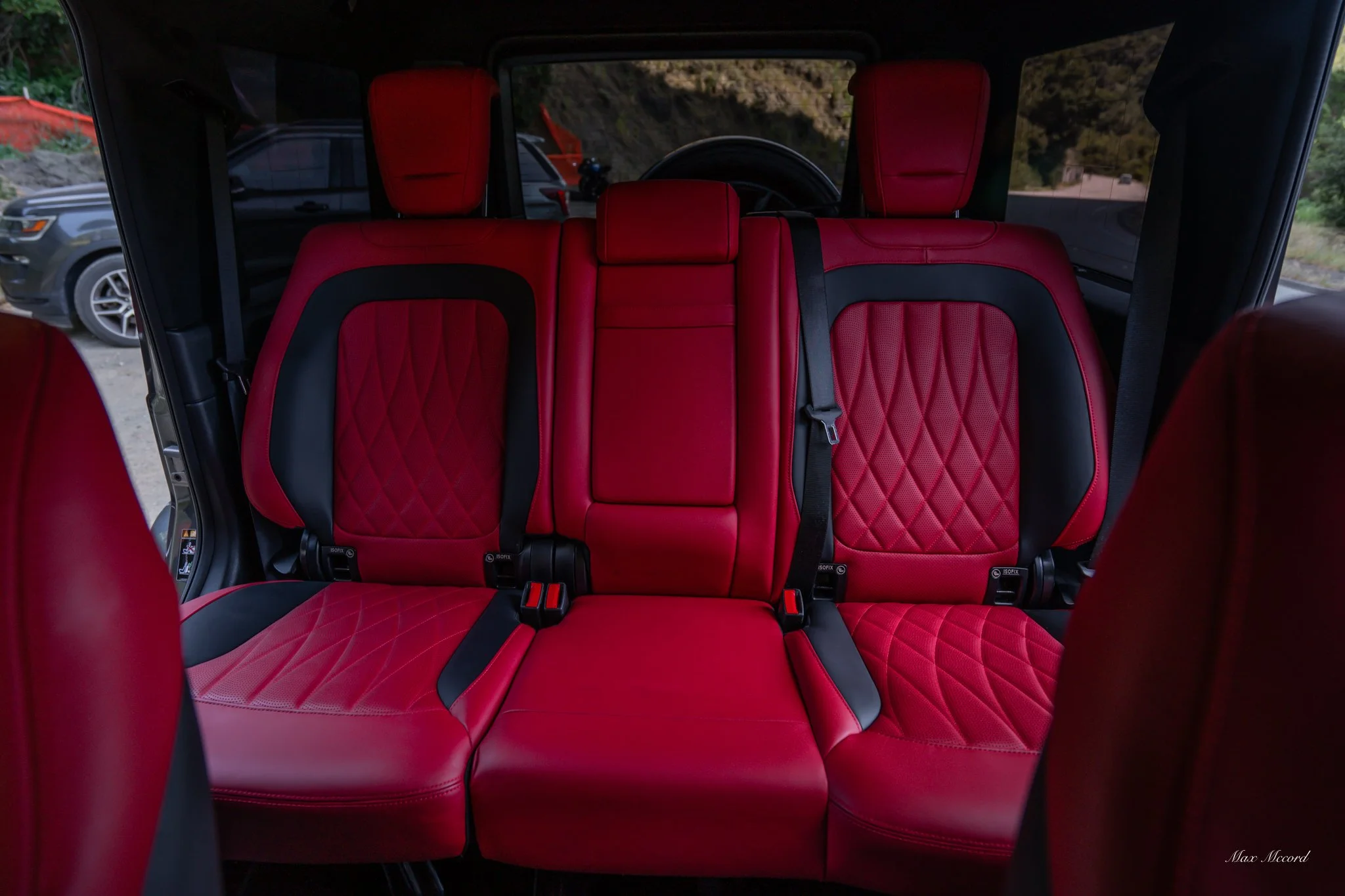 Red and black leather car seats inside an SUV, with the outside landscape visible through the windows.