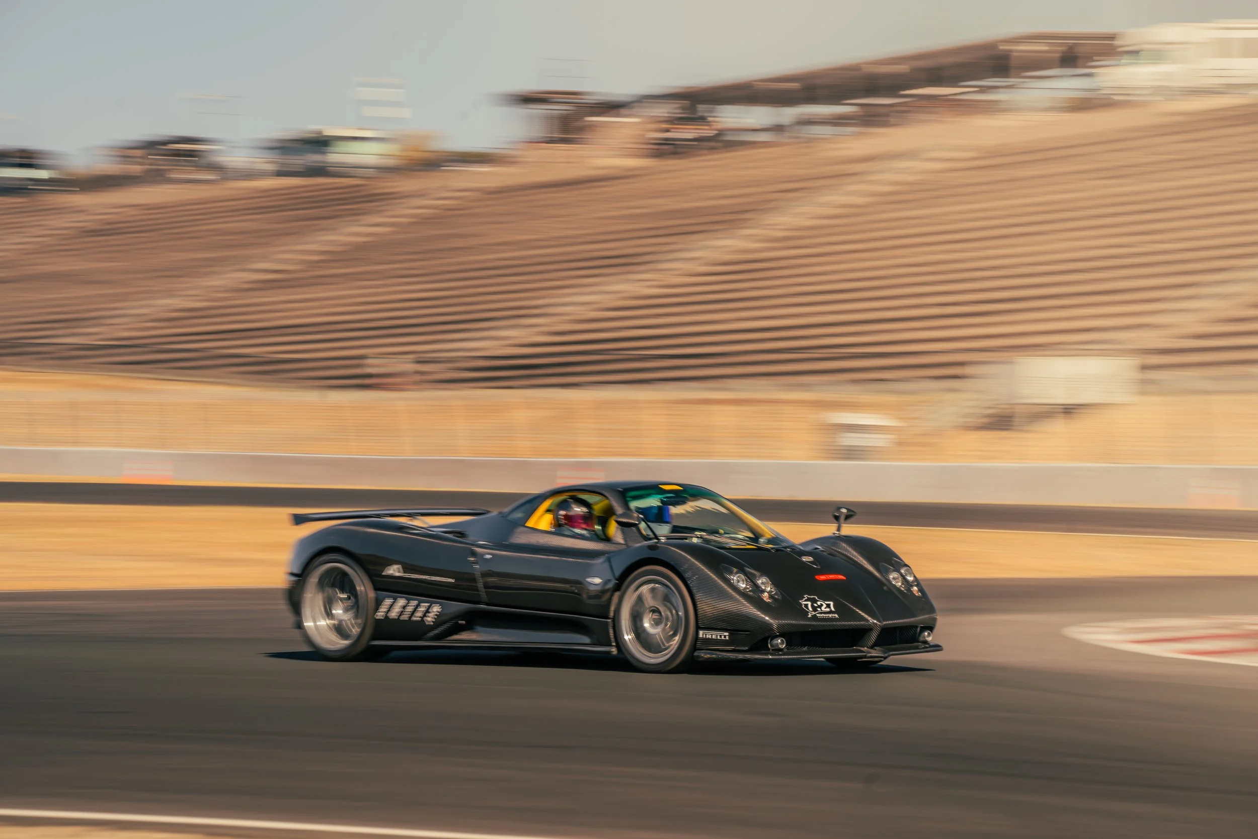 Black race car speeding on a race track with a blurred background.