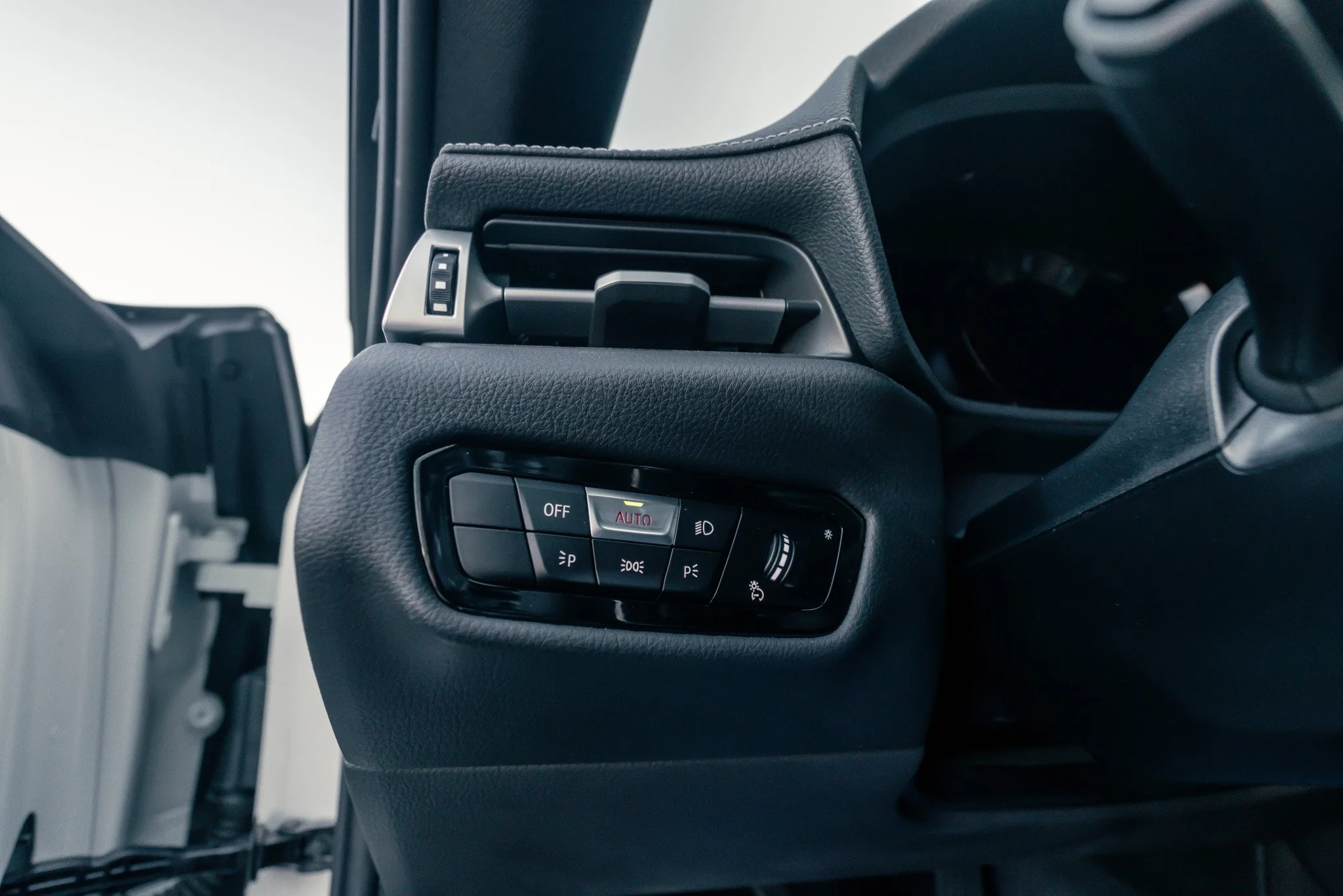 Close-up of a vehicle dashboard's air vent and control panel, with buttons for lights, auto mode, and brightness adjustment.