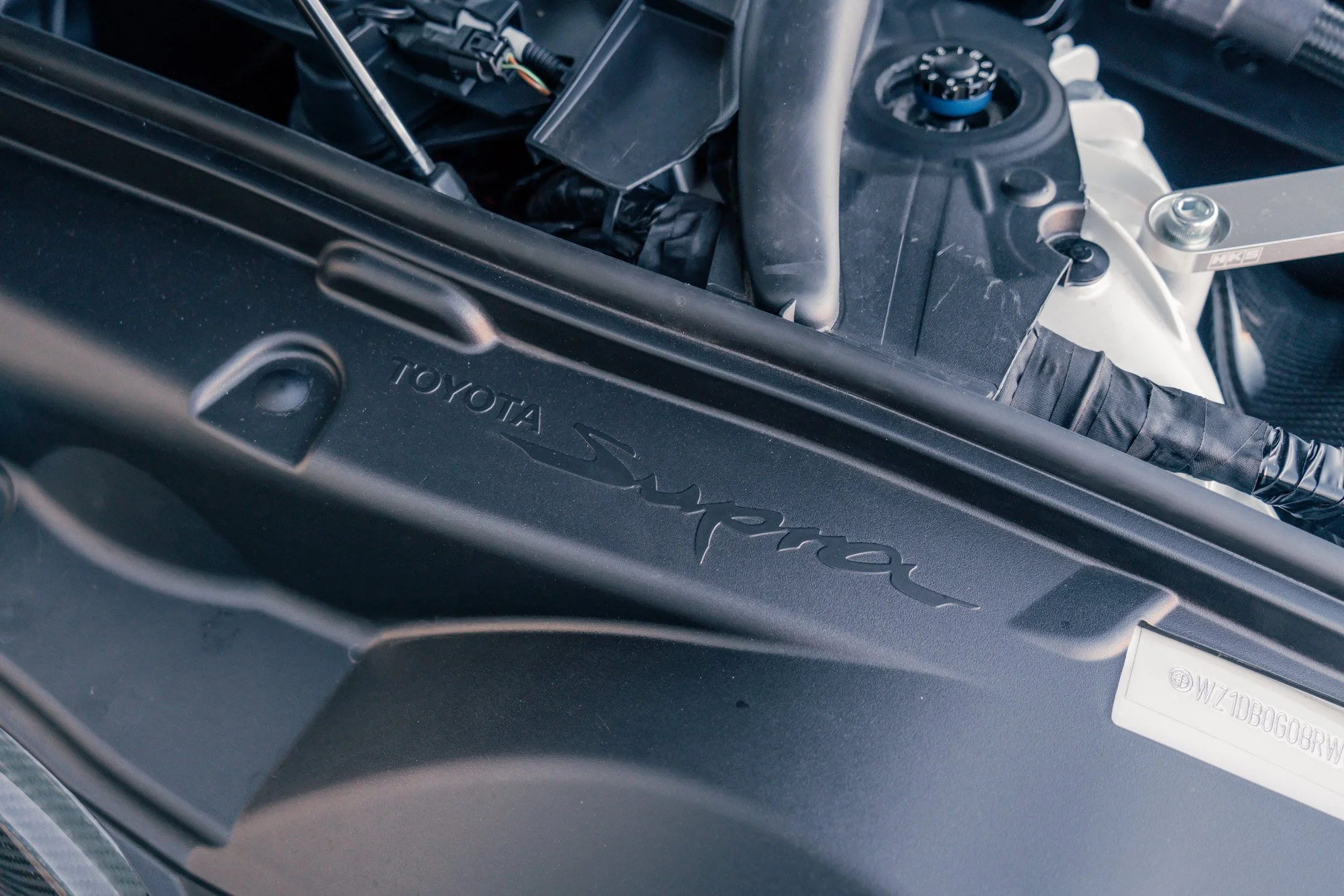 Close-up of a Toyota Supra engine bay featuring engine cover with the Toyota Supra logo.