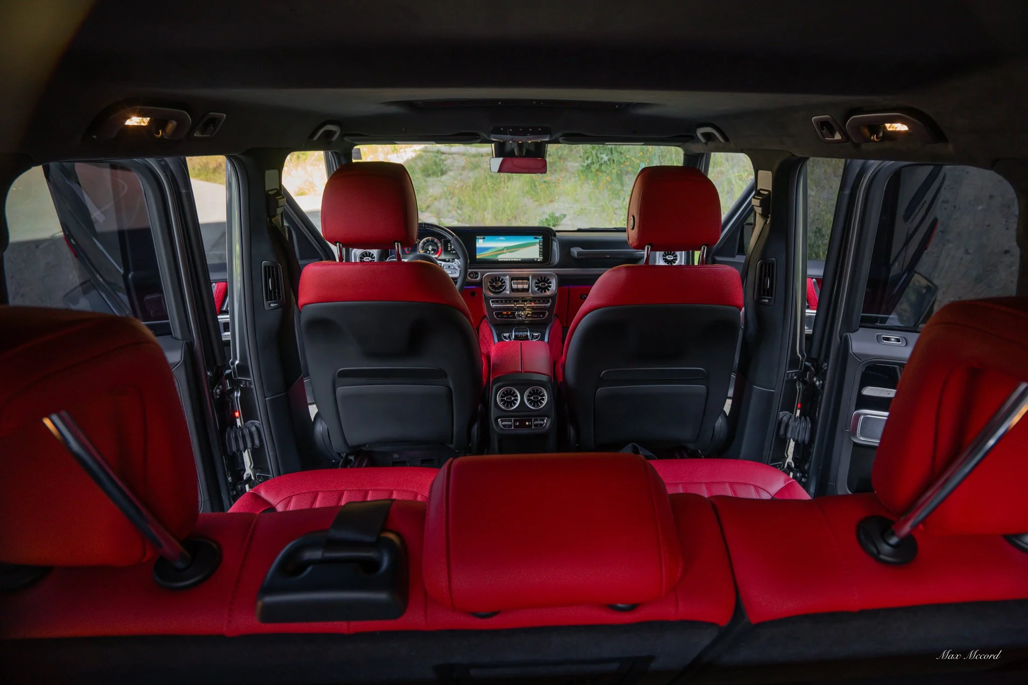 The interior of a luxury SUV with red leather seats and a modern dashboard, showing the front and rear passenger seats.