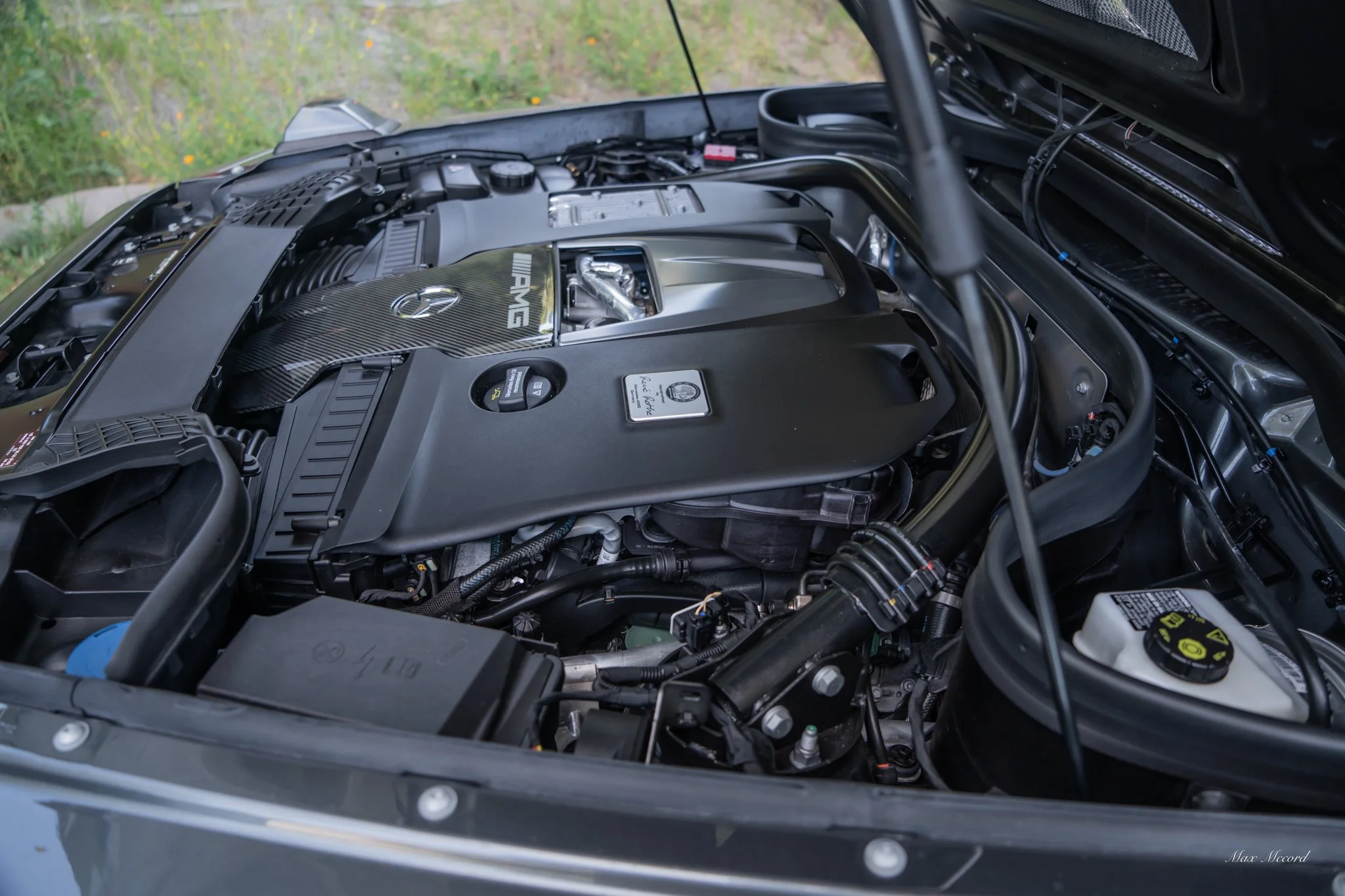 Close-up of a Mercedes-AMG car engine under the hood, showing detailed components and covers.
