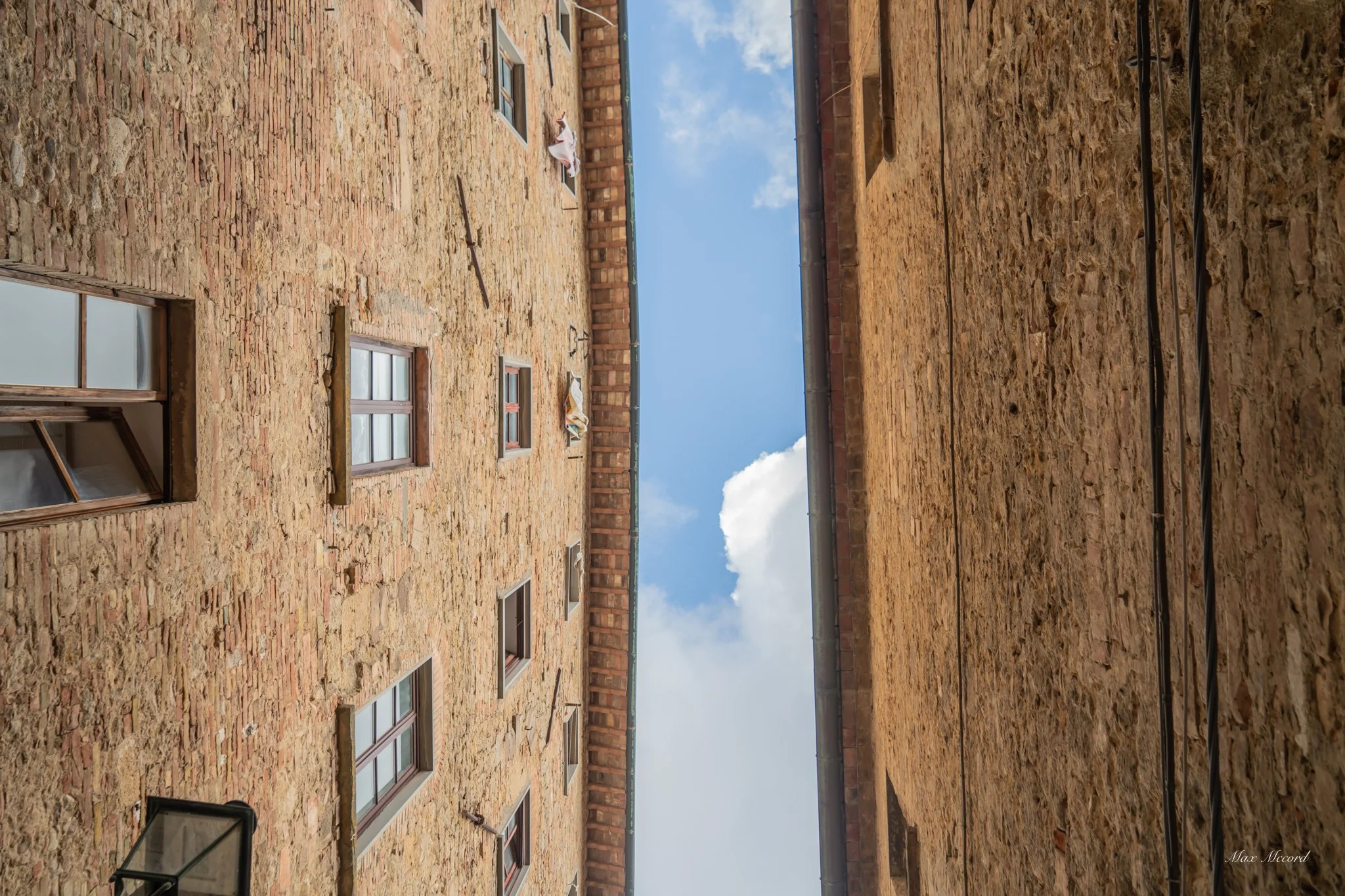 Facade of a brick building with multiple windows and a clear blue sky above.