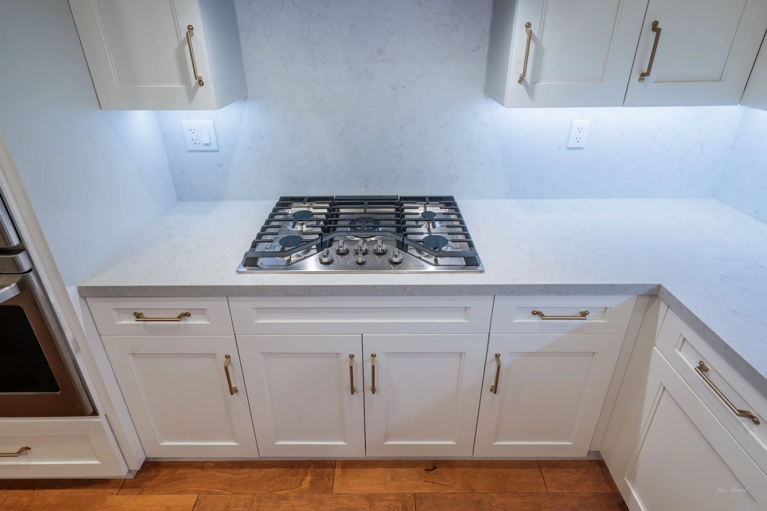 Kitchen with white cabinets, a gas stove, and hardwood flooring.