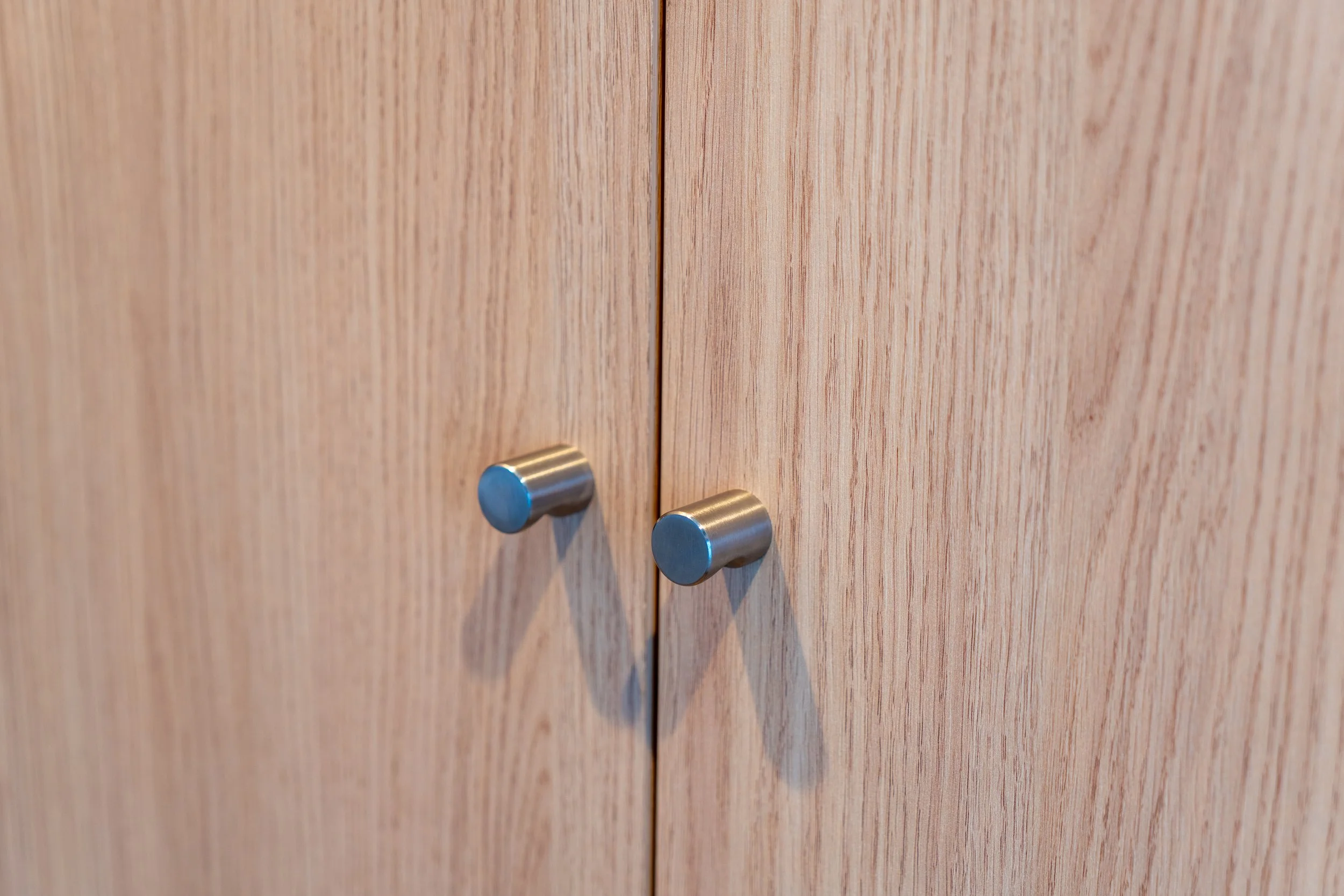 Close-up of two wooden cabinet doors with metal knobs.