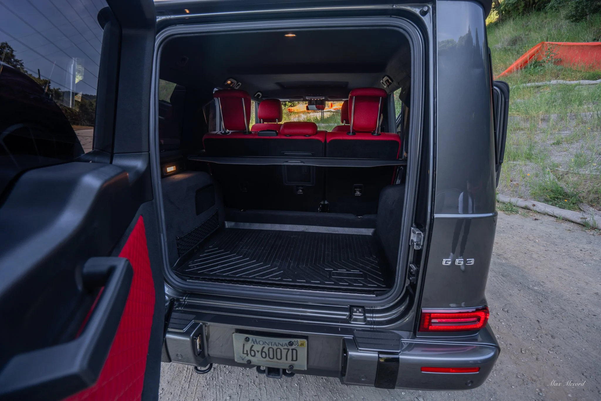 Open rear of a black Mercedes-Benz G63 SUV showing empty cargo space with red seats in the background