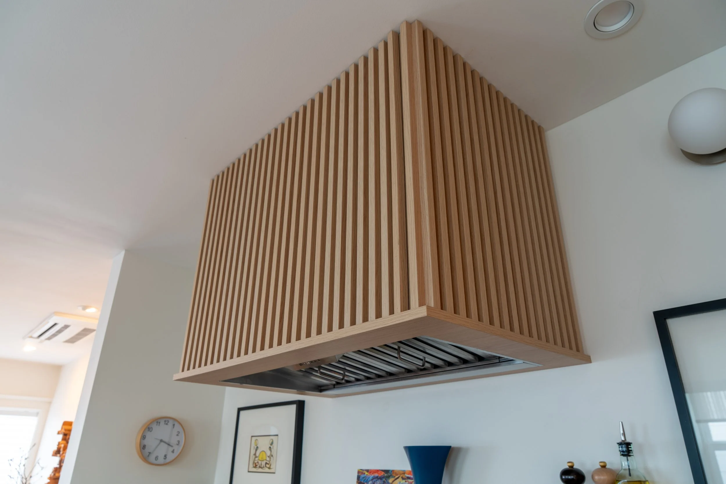 Ceiling-mounted kitchen range hood with a wooden slat exterior design.