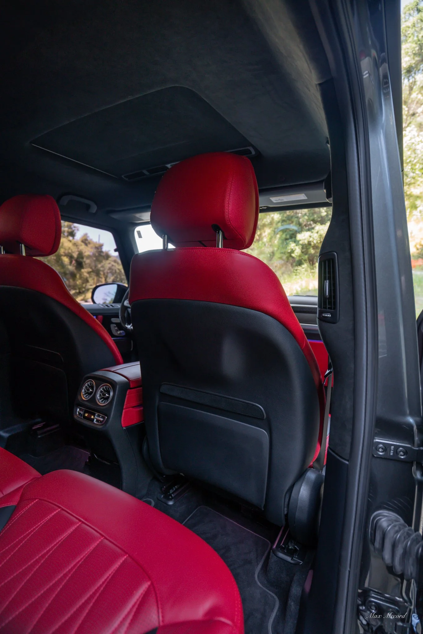 The interior of a vehicle showing red leather seats and black interior accents, with rear air vents visible between the seats.