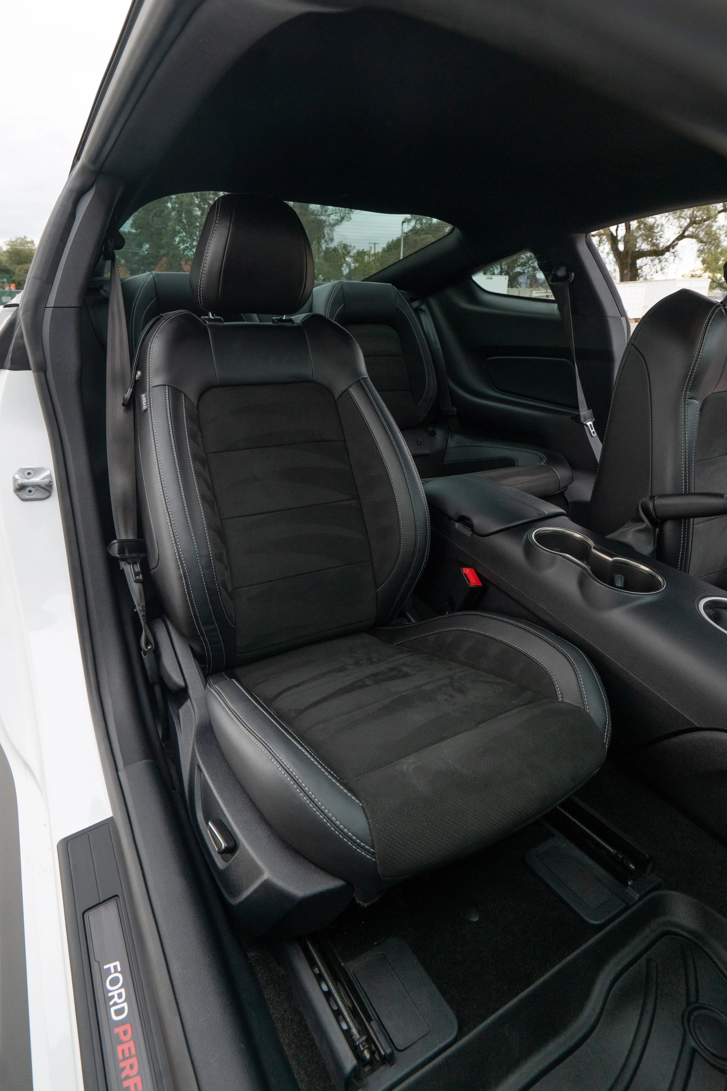 The interior of a white Ford performance vehicle showing the black front seats, center console, and part of the back seat.