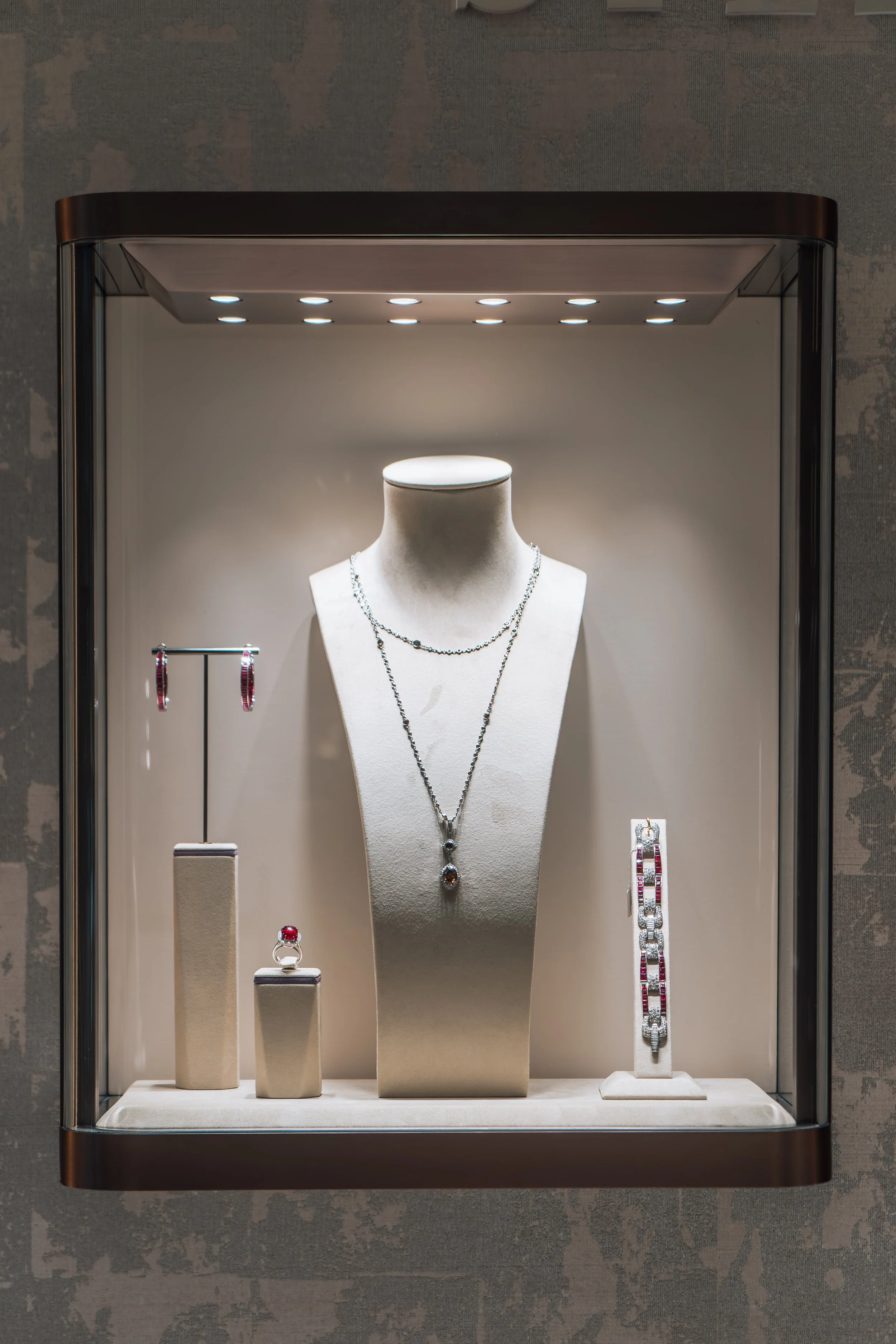 Display of jewelry including necklaces, rings, earrings, and bracelets in a glass case.