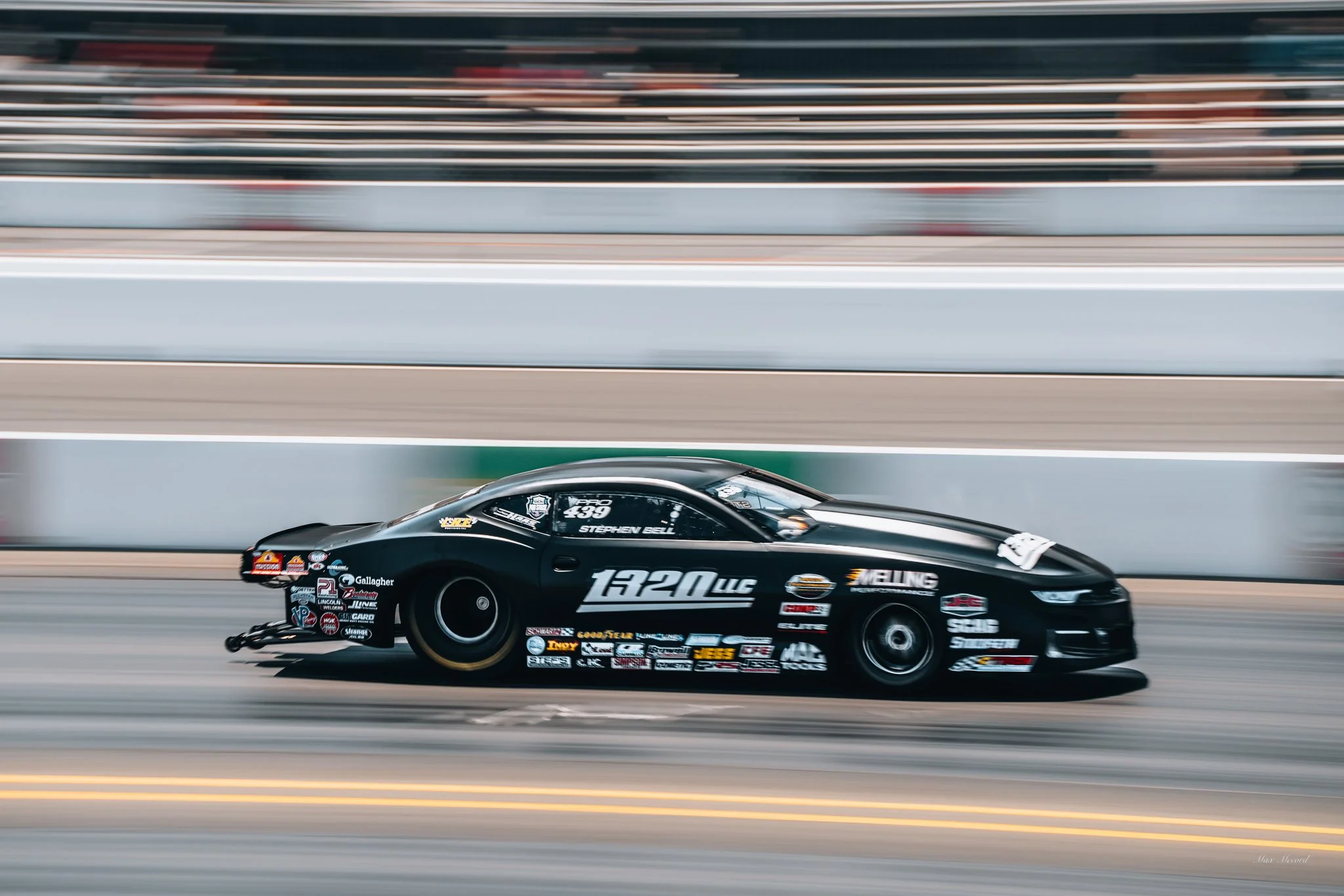Black drag racing car speeding on the track with motion blur background