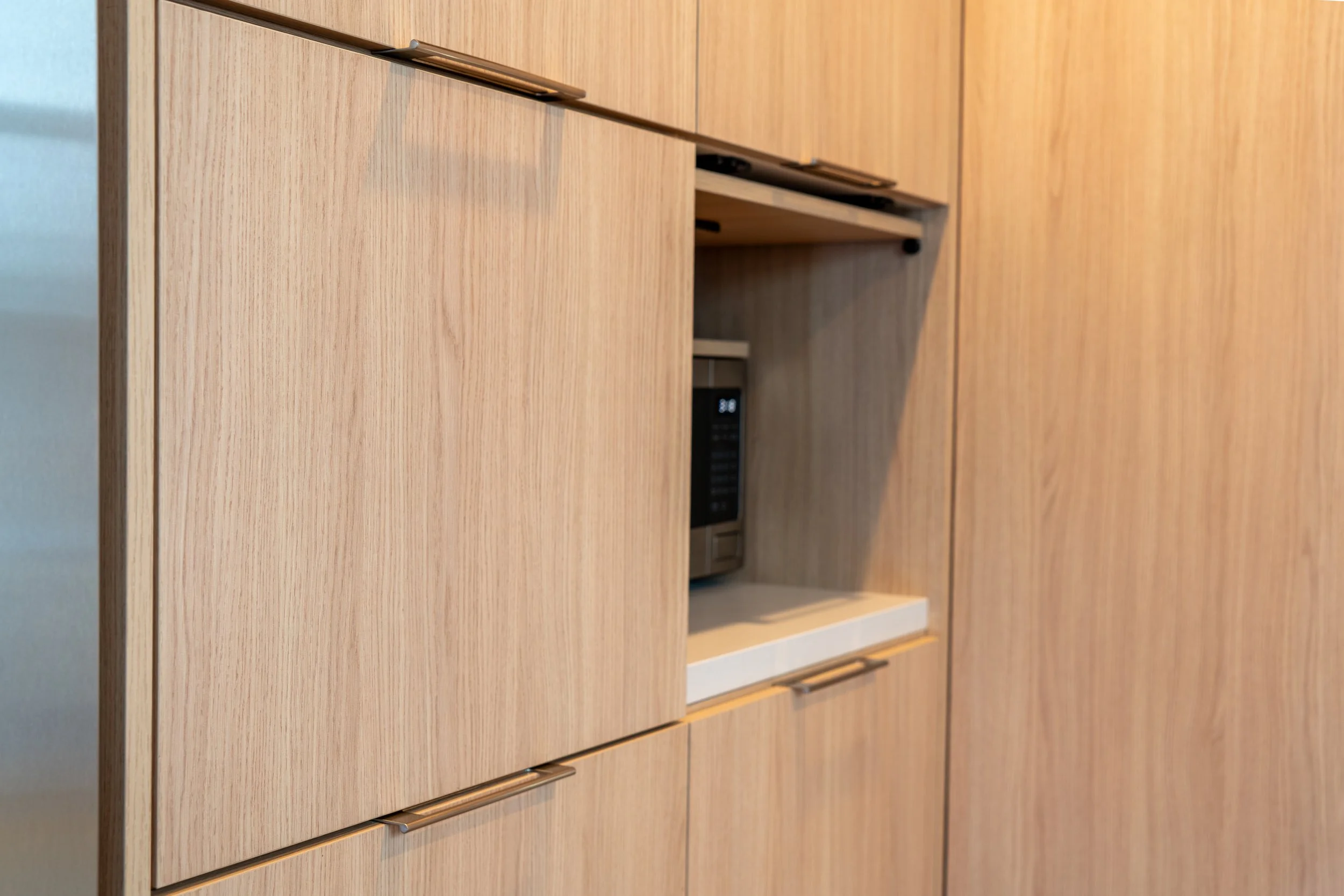 A built-in wooden cabinet with a microwave oven in a kitchen.