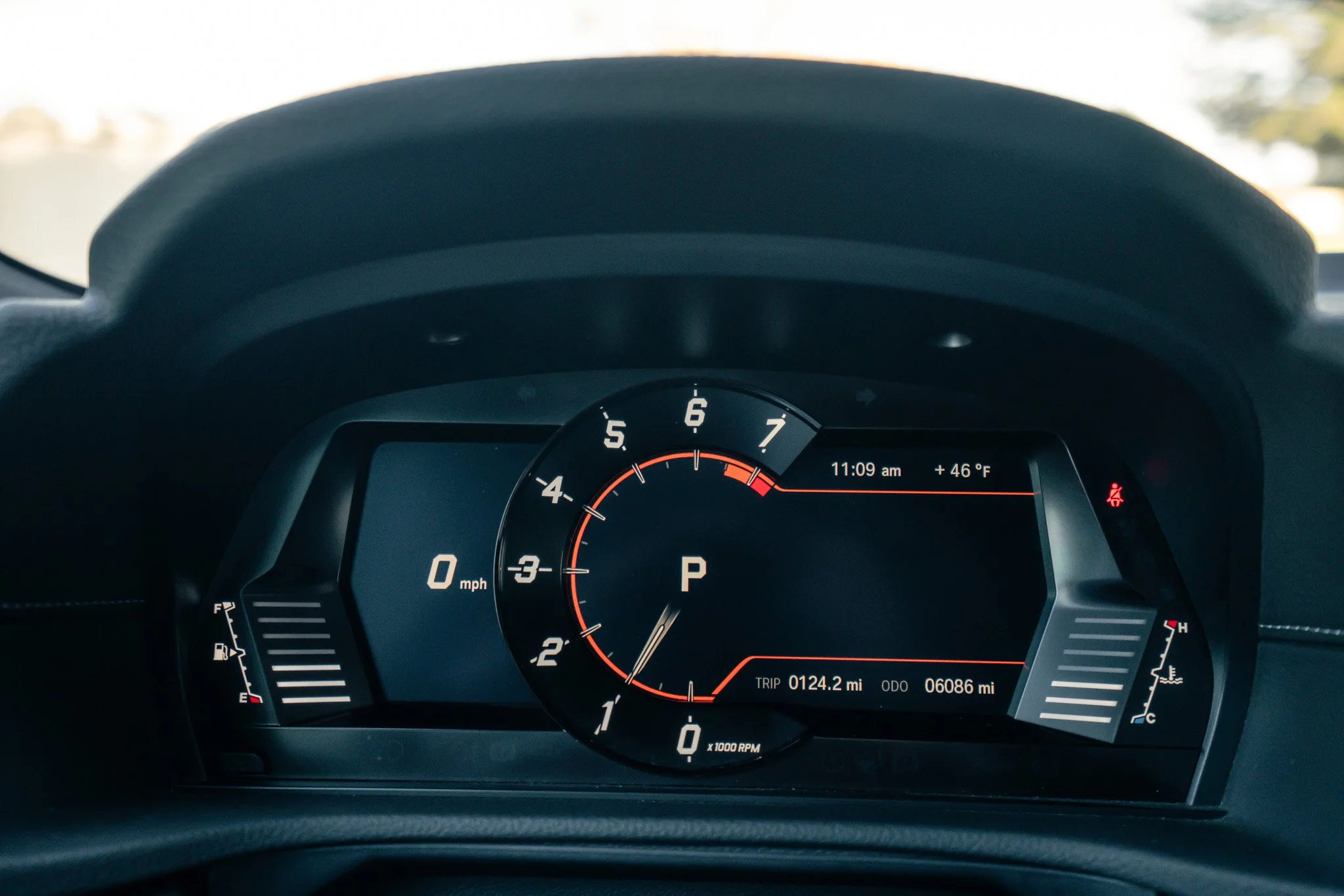Car dashboard showing speed at 0 mph, gear in park, tachometer below 1, fuel gauge mostly full, temperature gauge in normal range, time at 11:09 am, temperature at 46°F, and odometer reading 6,086 miles.