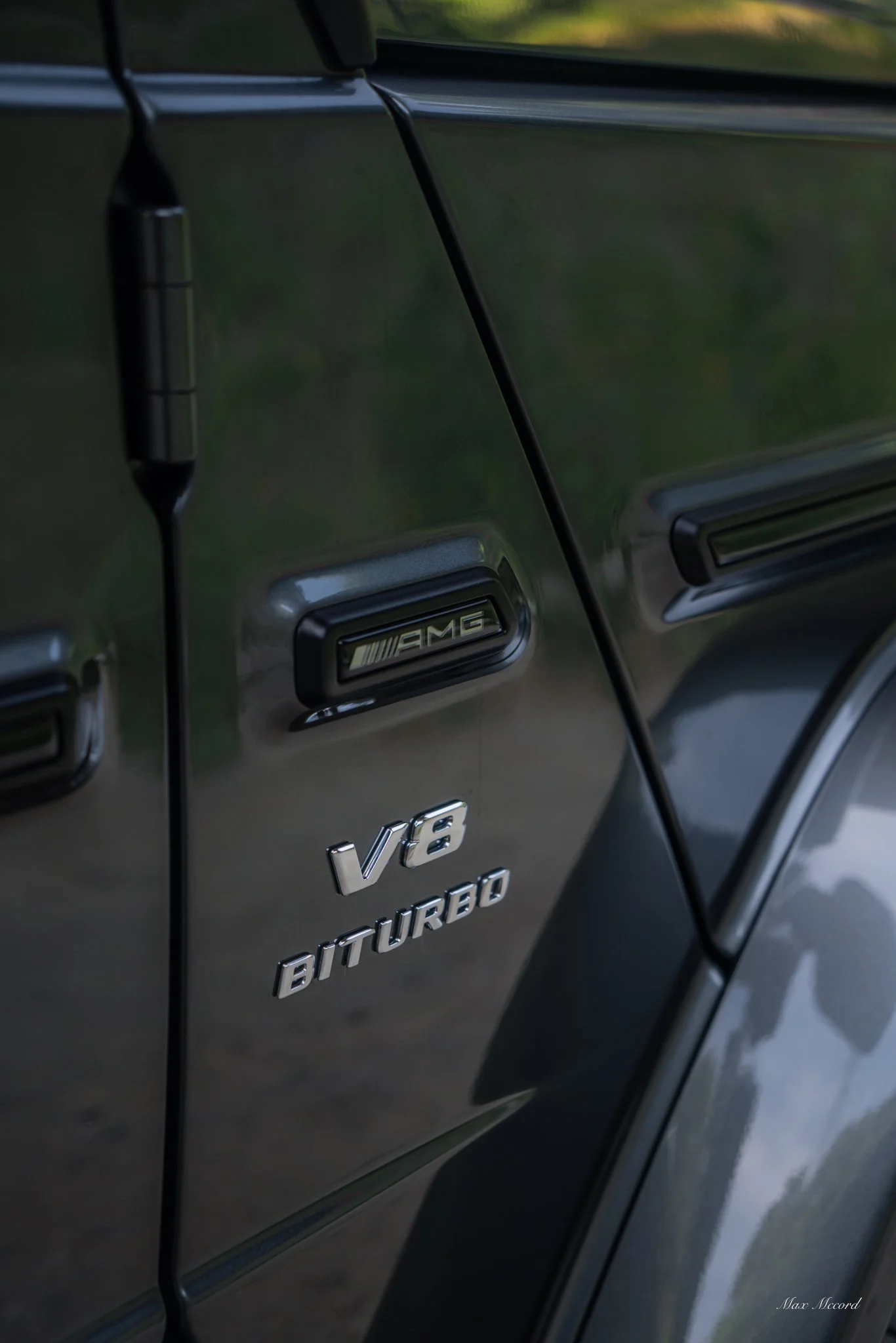 Close-up of a black Mercedes-Benz vehicle with AMG badge, V6 Turbo and logo, and an antenna on the side.