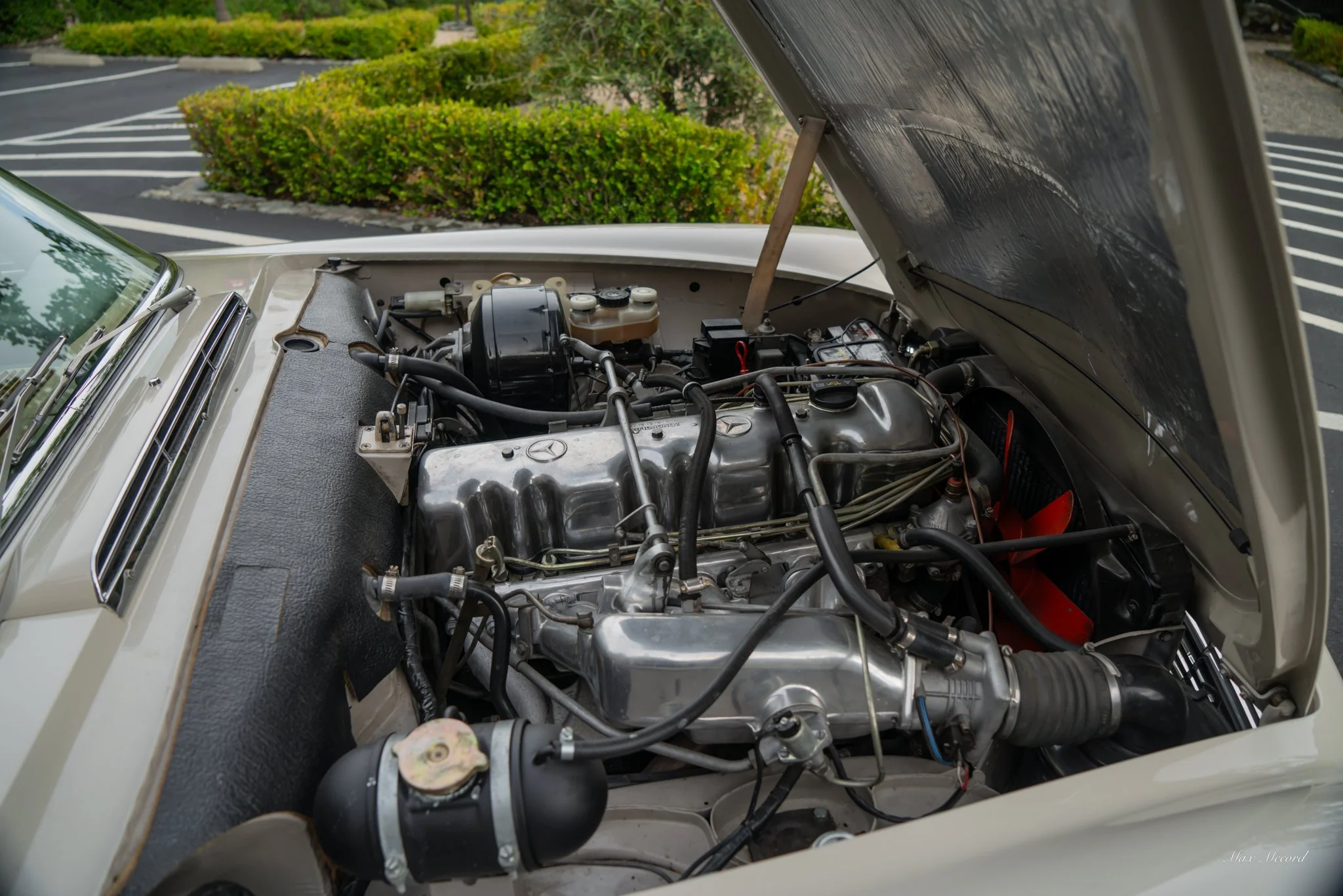 View of the open hood of a vintage Mercedes-Benz car showing the engine and various mechanical components.