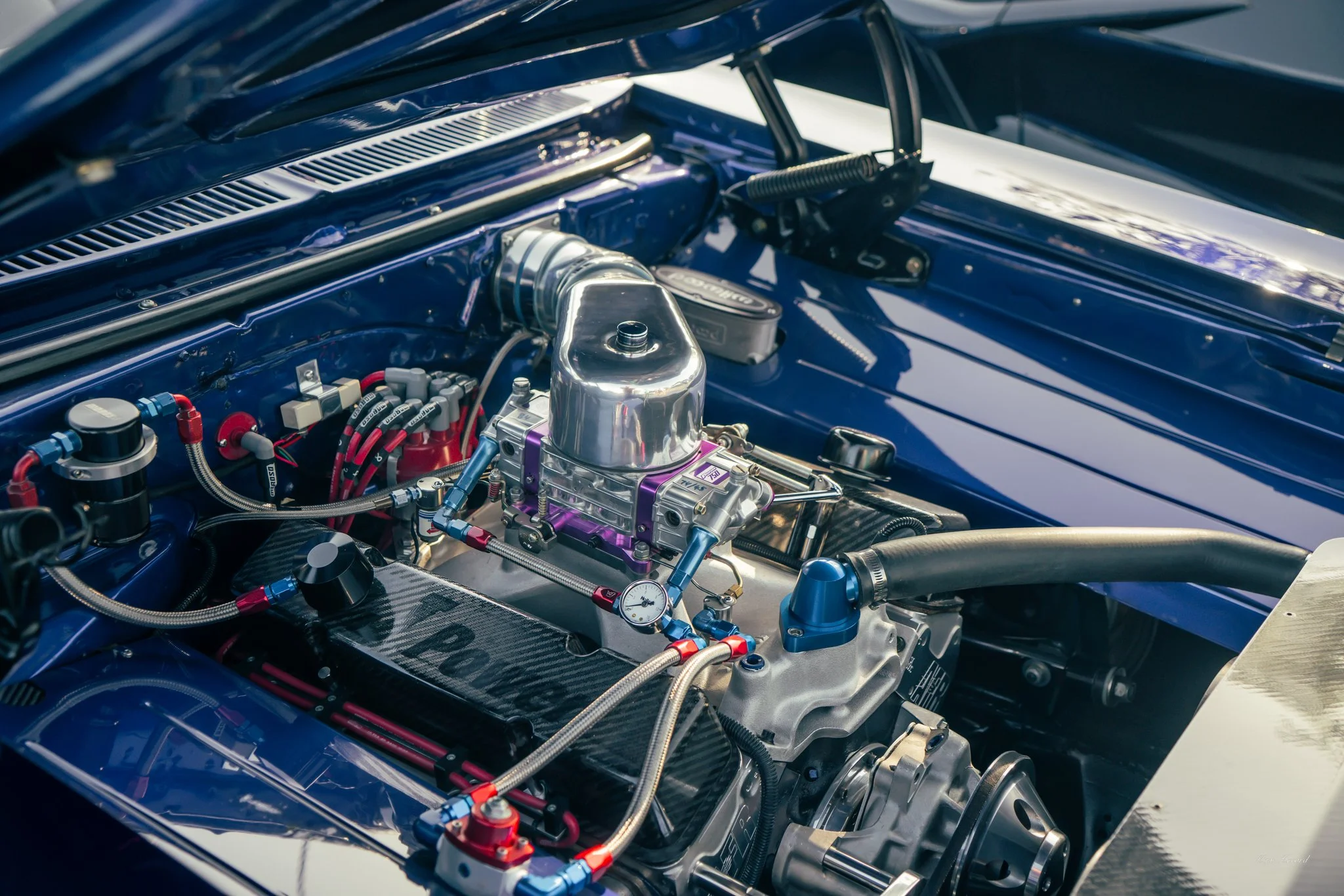 Close-up of a racing car engine bay with various colorful components and polished metal parts.