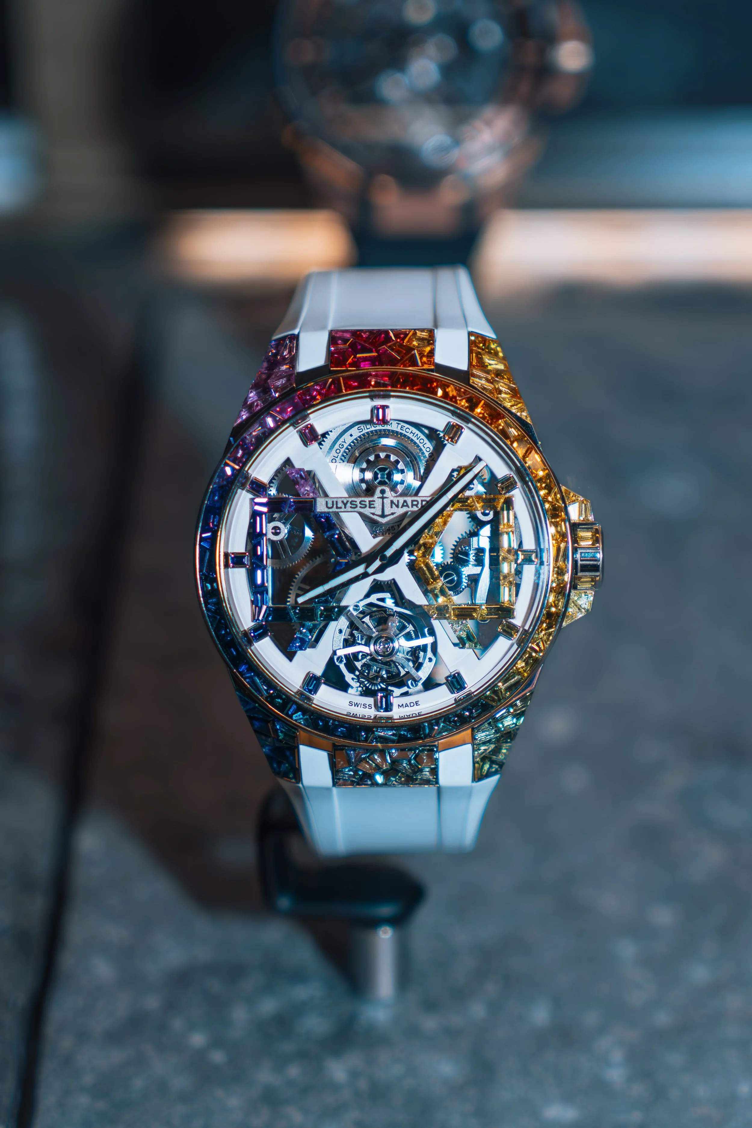 Close-up of a luxury Ulysse Nardin wristwatch with a white strap, showcasing its intricate skeleton dial and gold accents.