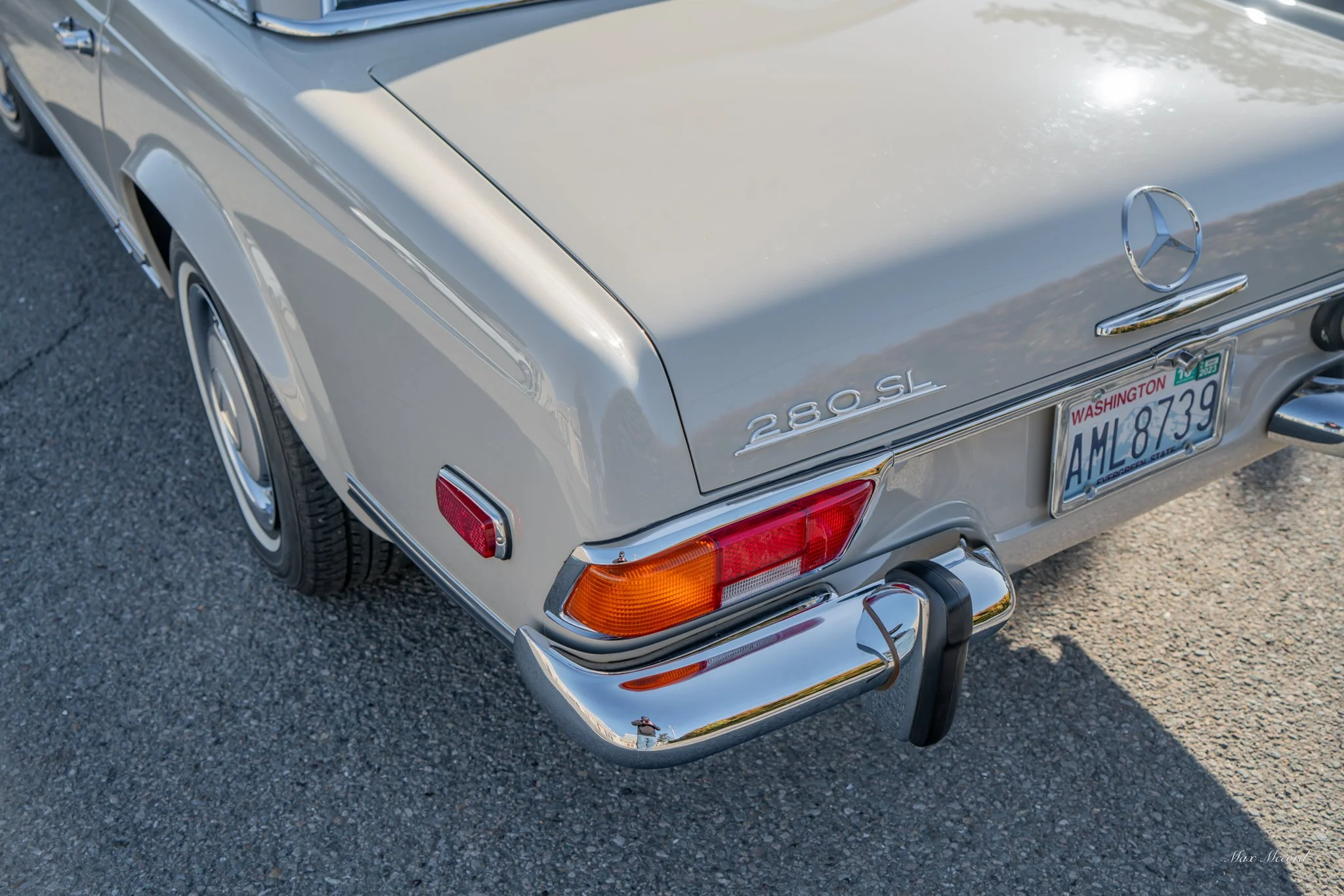 Rear view of a vintage silver Mercedes-Benz 280 SL with Washington license plate AML 8739, showing tail lights, bumper, and Mercedes logo.
