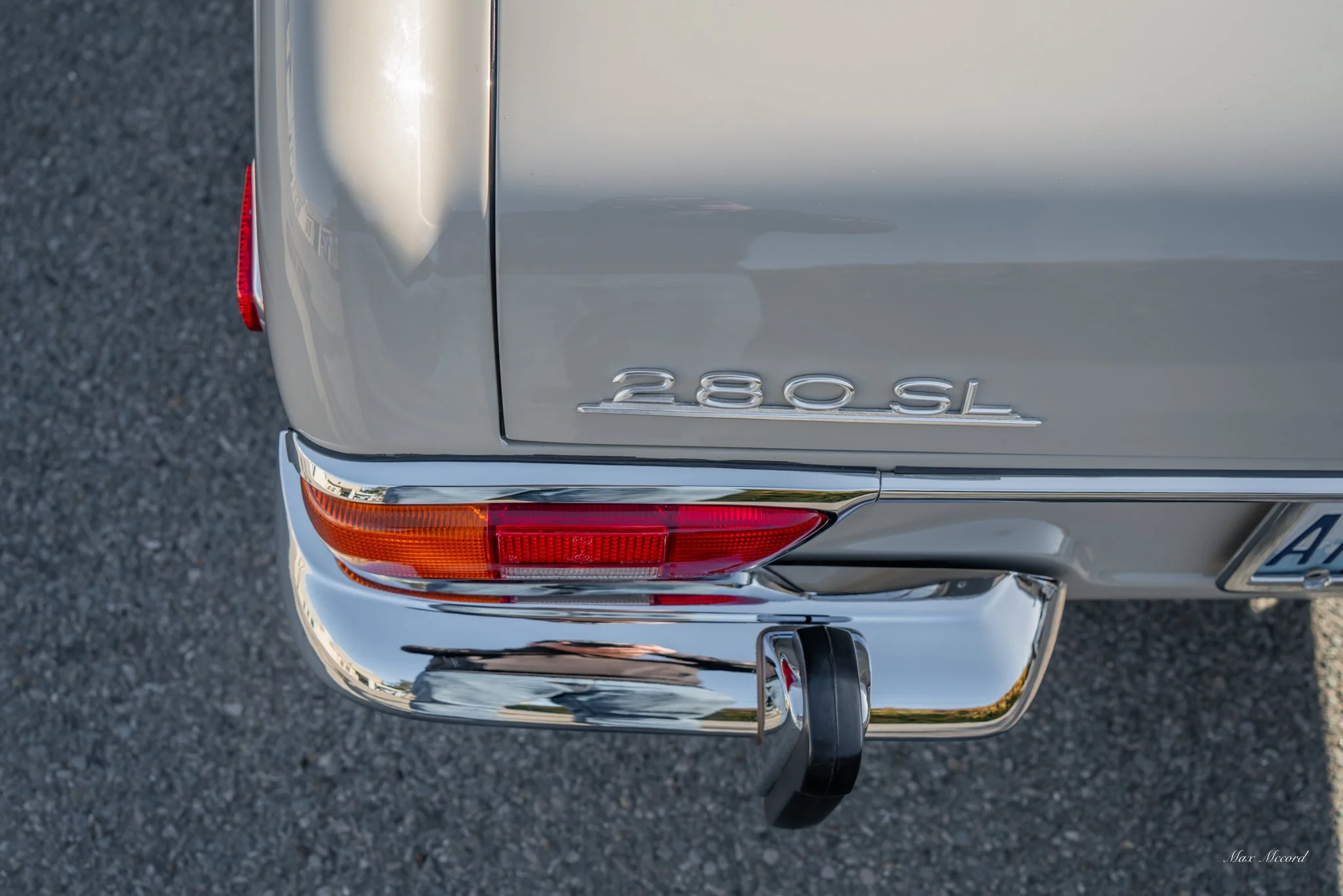 Close-up of the rear of a silver Mercedes-Benz 280 SL, showing the tail light, bumper, and the model badge '280 SL' on the trunk.