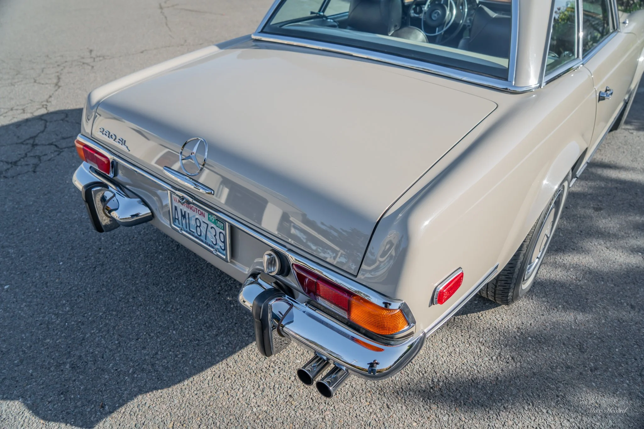 Rear view of a beige classic Mercedes-Benz 280SL convertible with dual exhaust pipes, chrome bumper, and Washington license plate.
