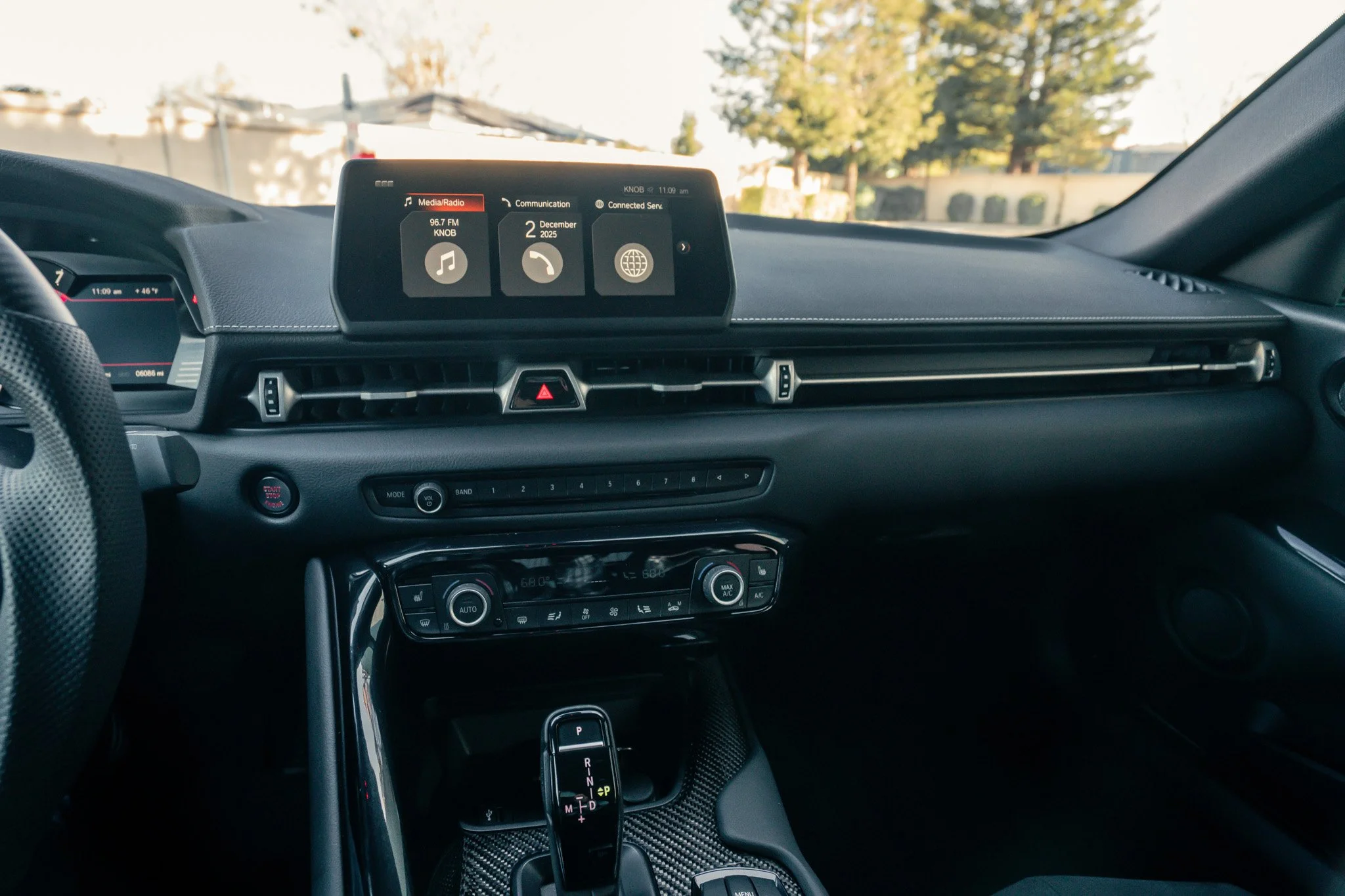 Interior of a modern car dashboard with a digital display screen, climate control panel, and gear shift.