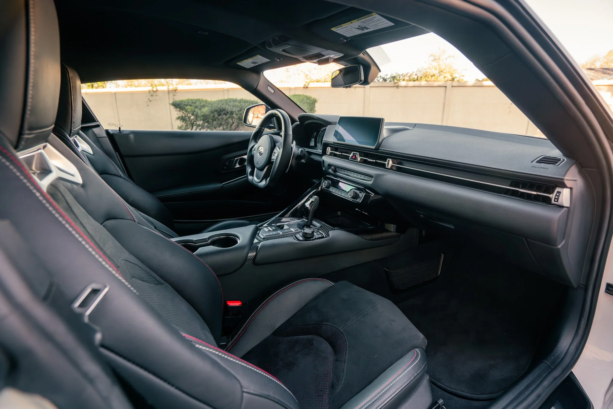 Interior of a modern sports car with black leather seats, a digital display on the dashboard, and a gear shift in the center console.