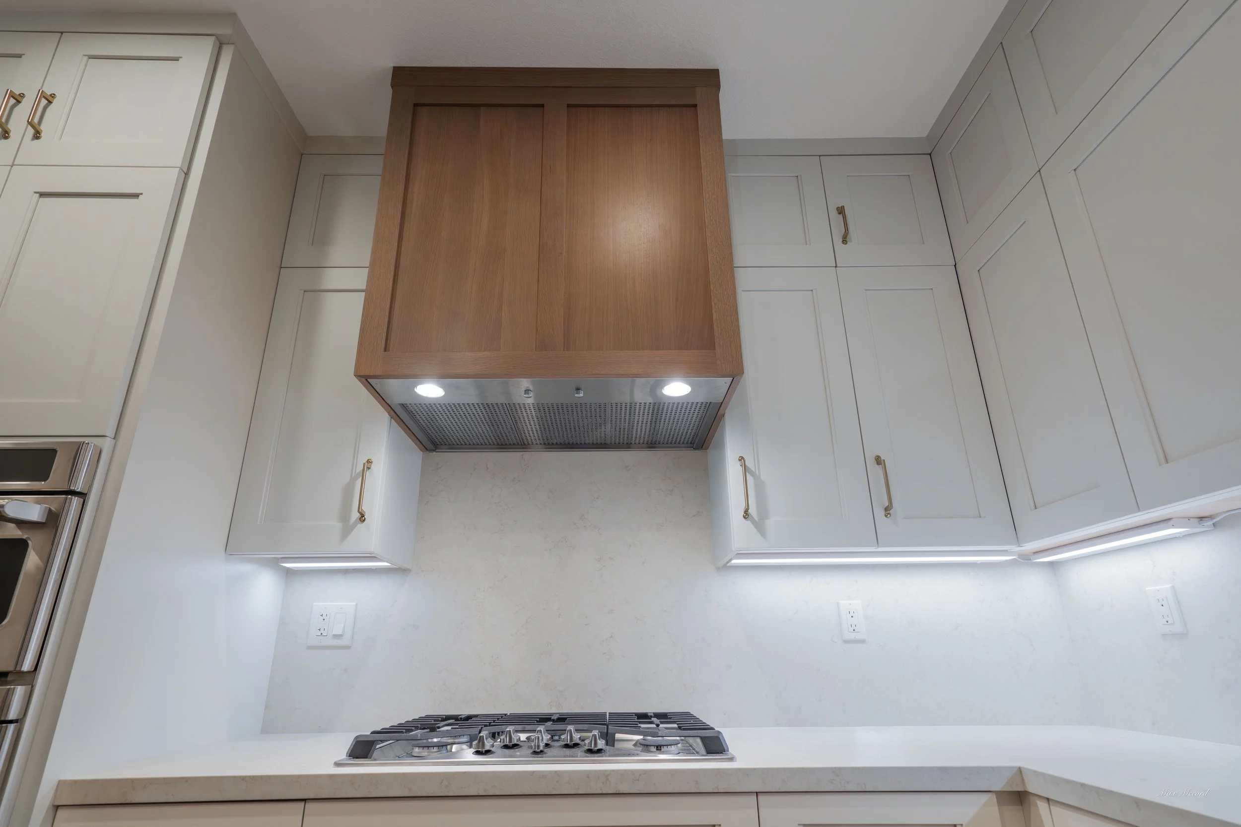 Kitchen with white cabinets, a wooden range hood, and a gas stove with four burners.