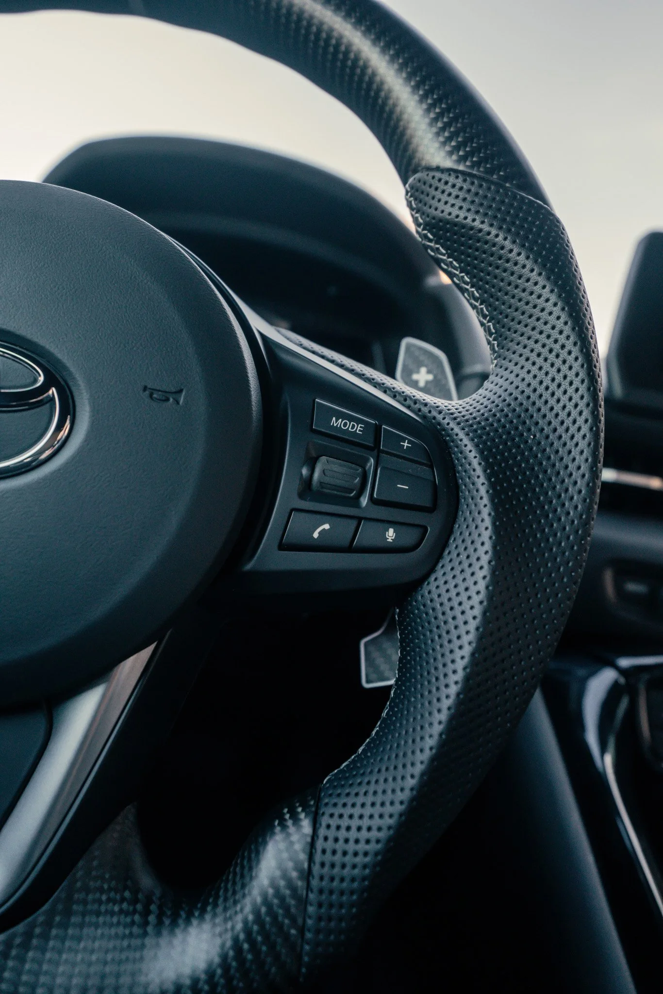 Close-up of a car's steering wheel with various control buttons on the right side.