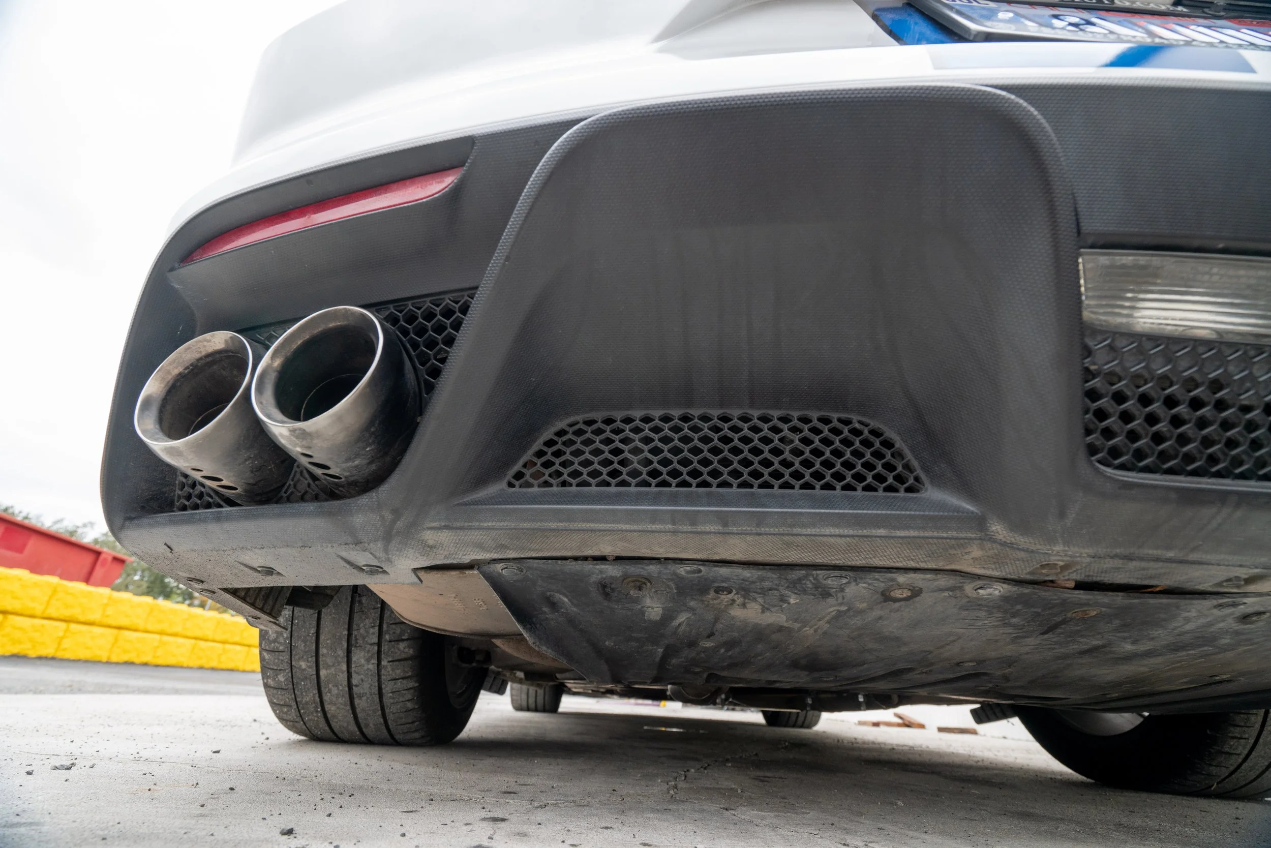Rear view of a sports car showing dual exhaust pipes and rear bumper with black and silver accents.