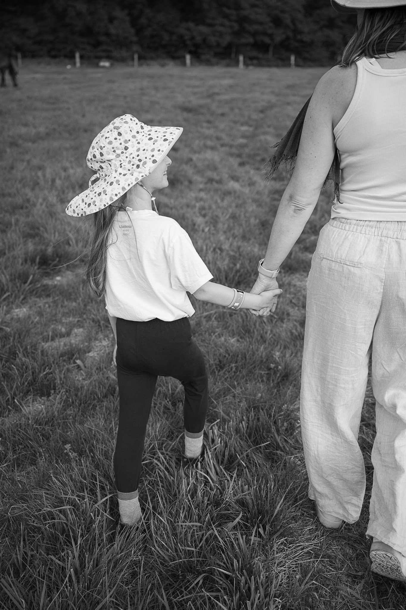 Ein Kind und seine Mama halten Händchen in einem Feld.