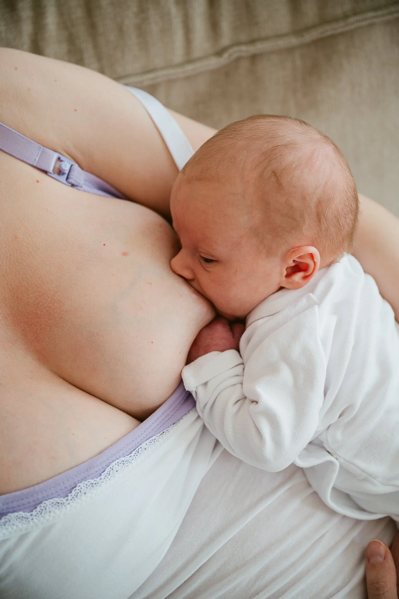 Ein Neugeborenes wird von seiner Mutter gestillt und liegt eng an ihrer Brust.