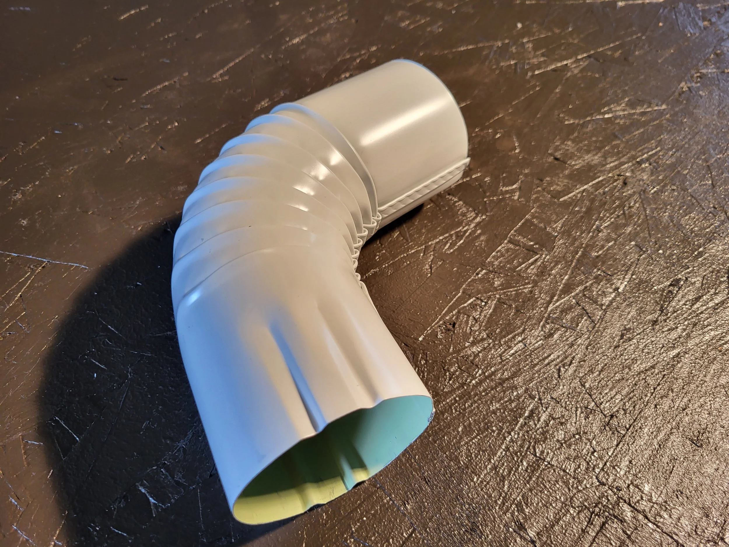 A white aluminum round downspout elbow.