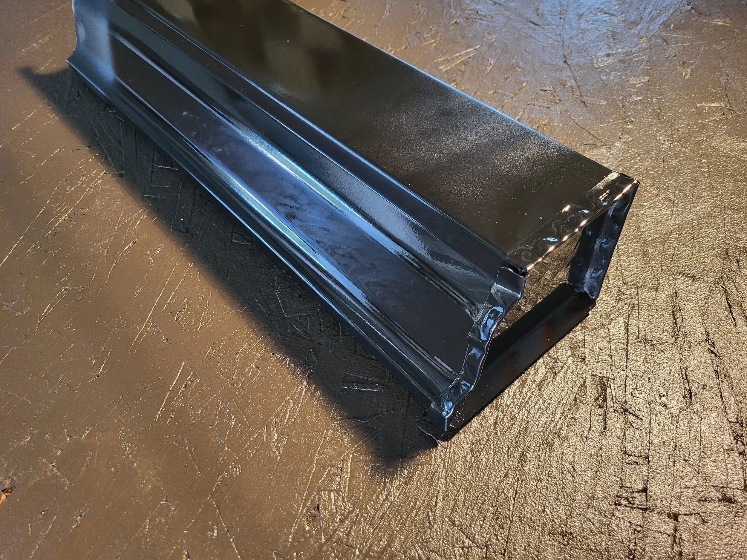 A closeup of a black 5 inch k style gutter from below and on the endcap