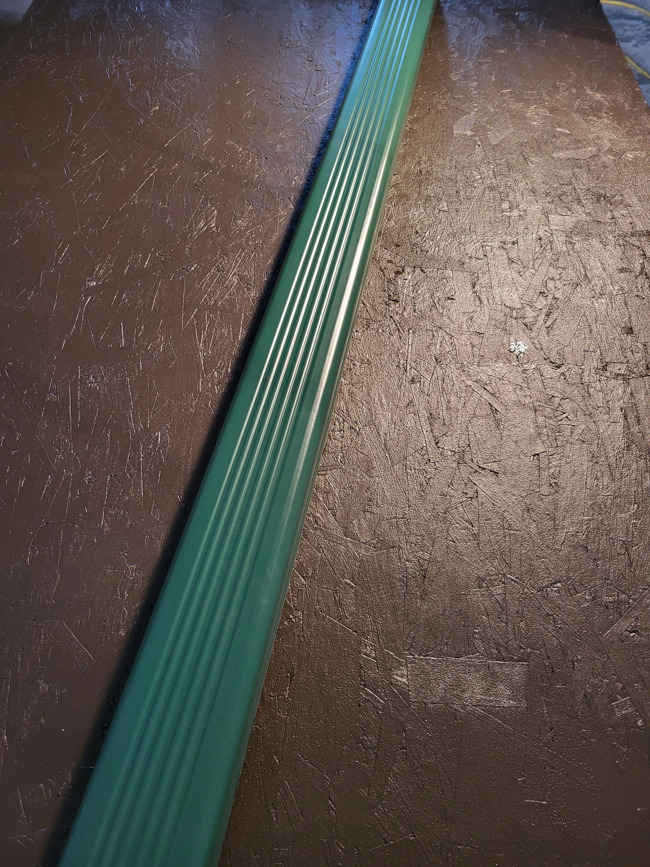 Close-up image of a green 3x4 inch corrugated aluminum downspout