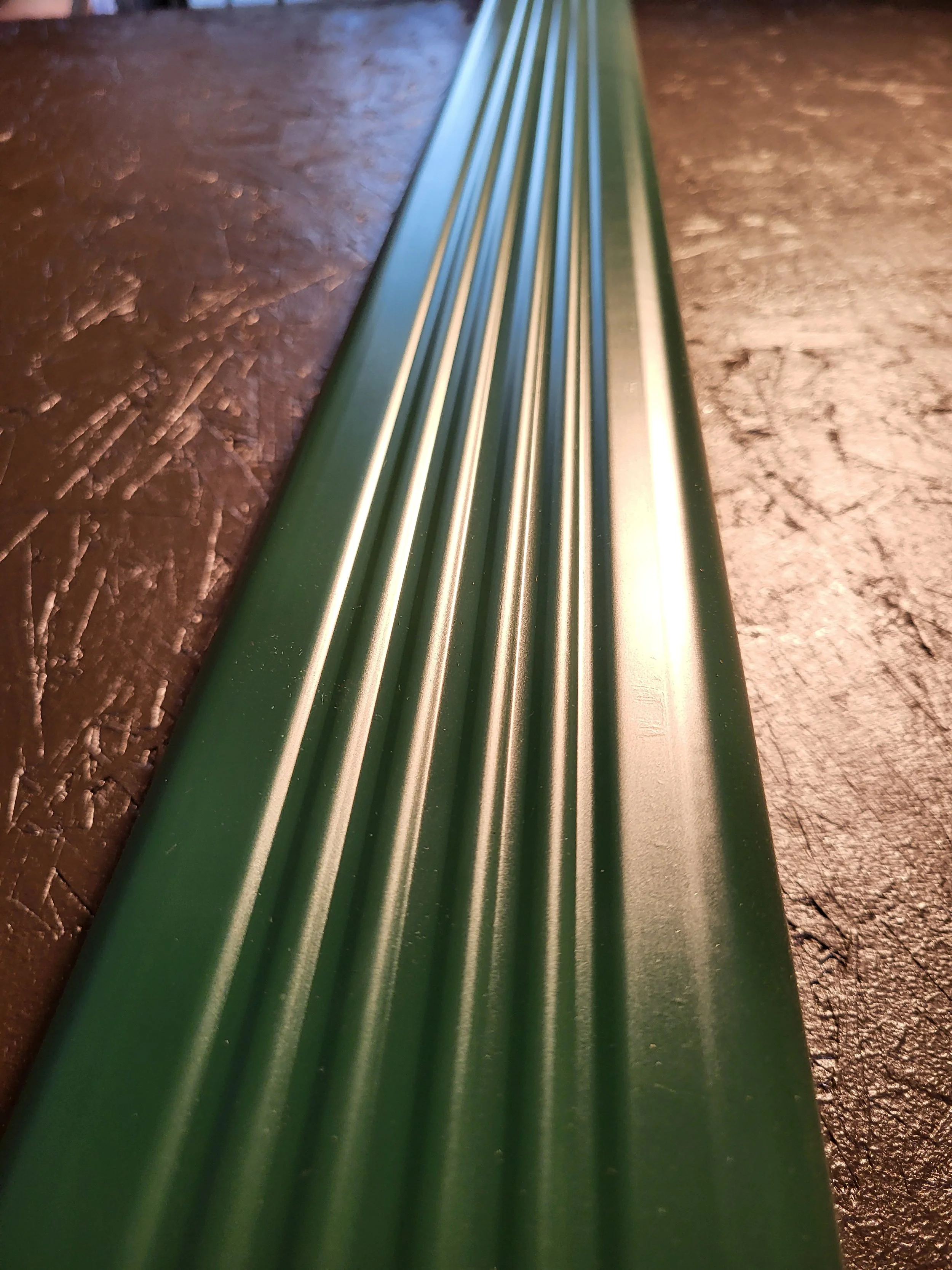 A close-up photo of a green metal corrugated downspout.