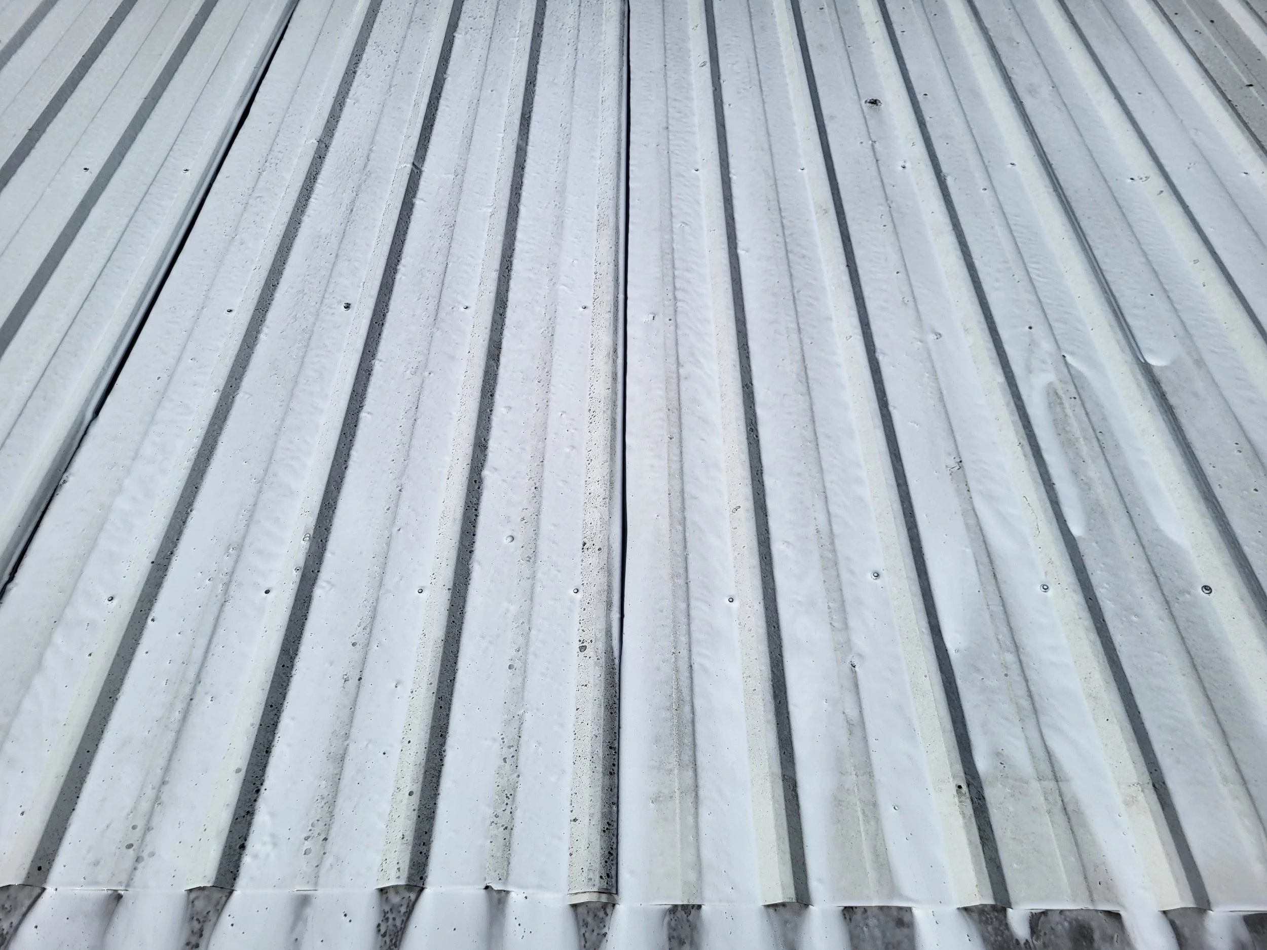 Close-up of a metal roof with black lines and some rust spots.
