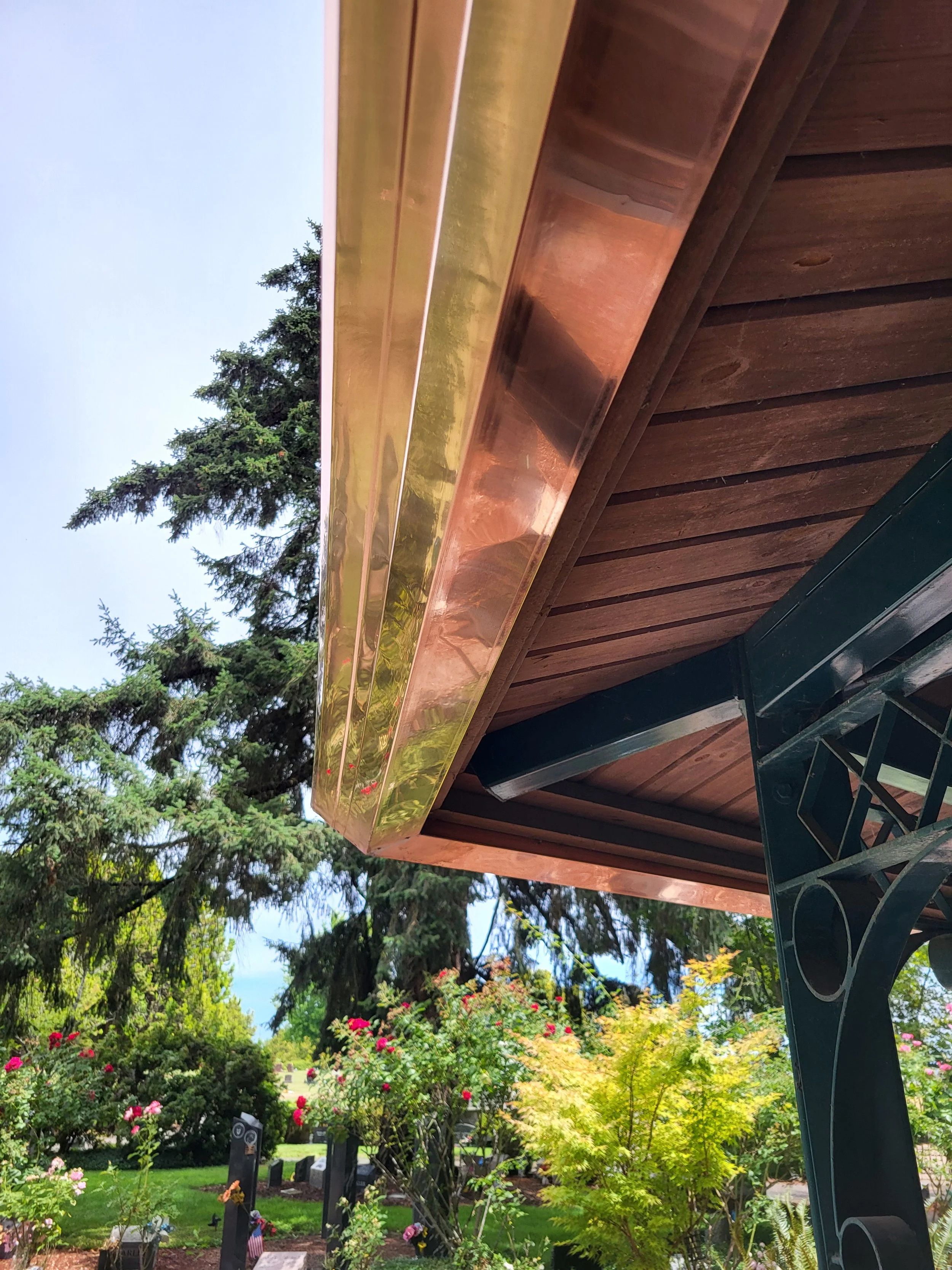 Copper gutter, Installed on a green metal gazebo, headstones on the ground in a lush garden