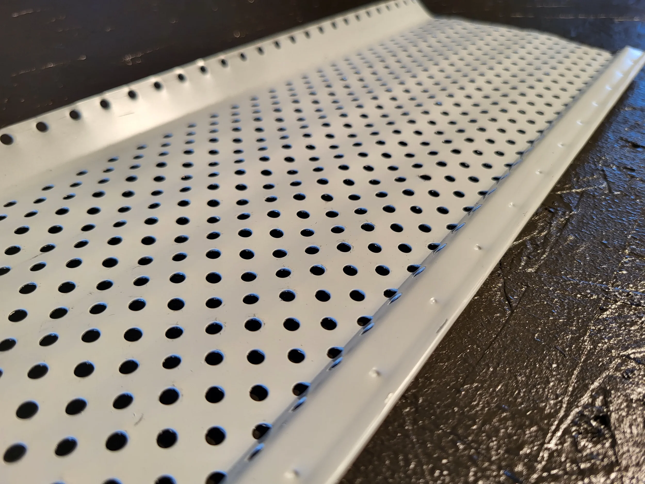 a closeup of a perforated mesh gutter screen.