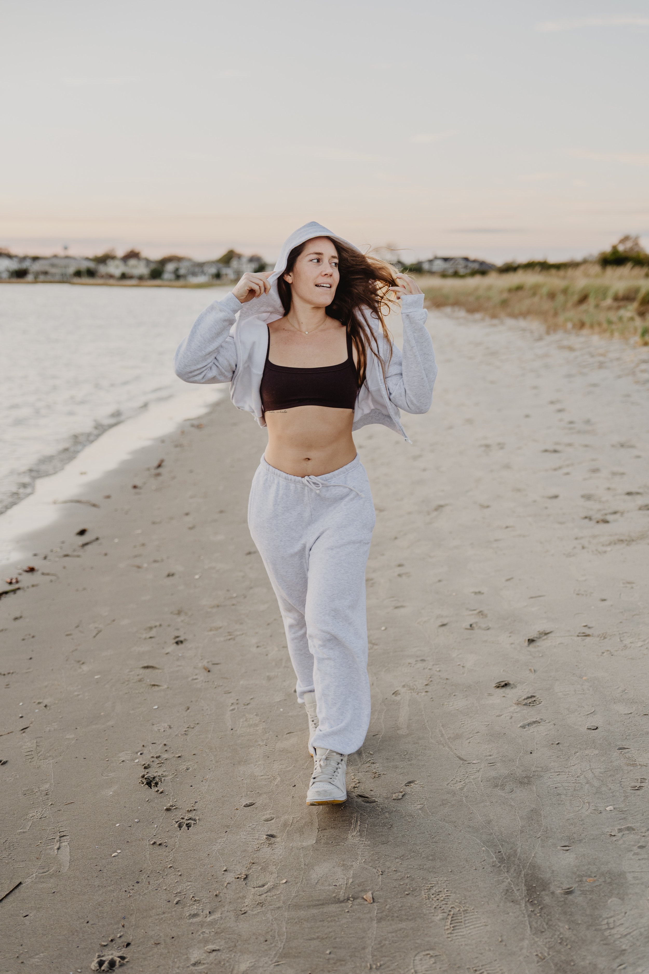 Woman in athletic wear jogging on a beach at sunset