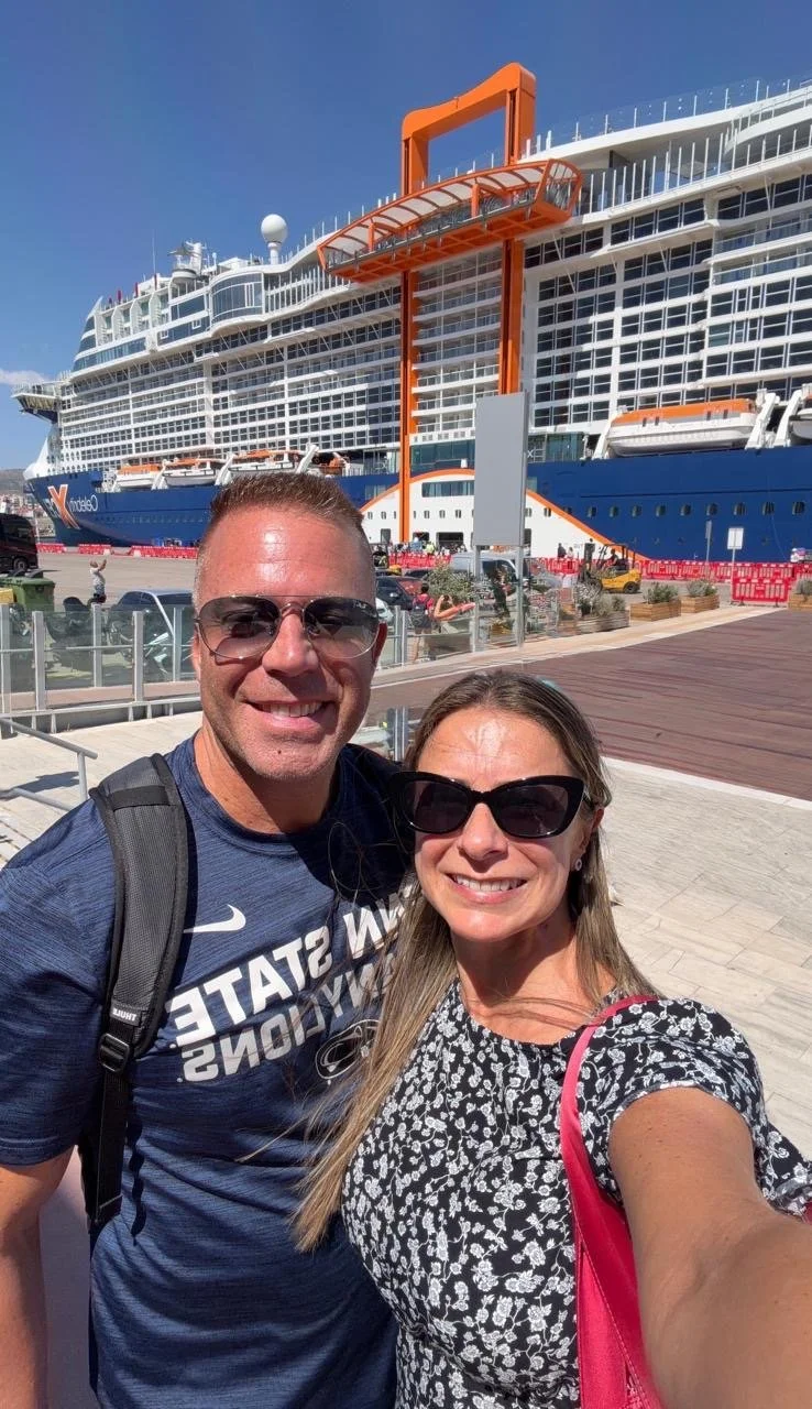 Honeymoon couple standing in front of a cruise ship.
