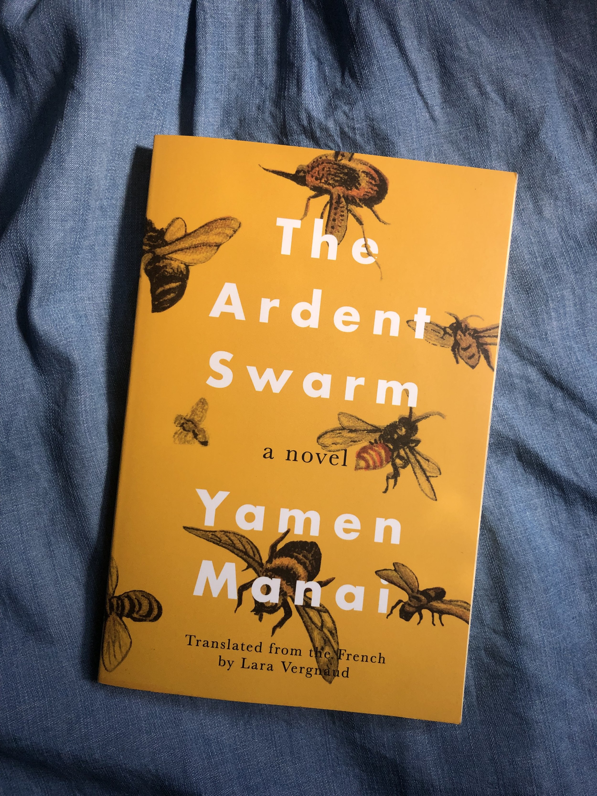 photo of the yellow cover of Yamen Manai's The Ardent Swarm book on a denim blue background